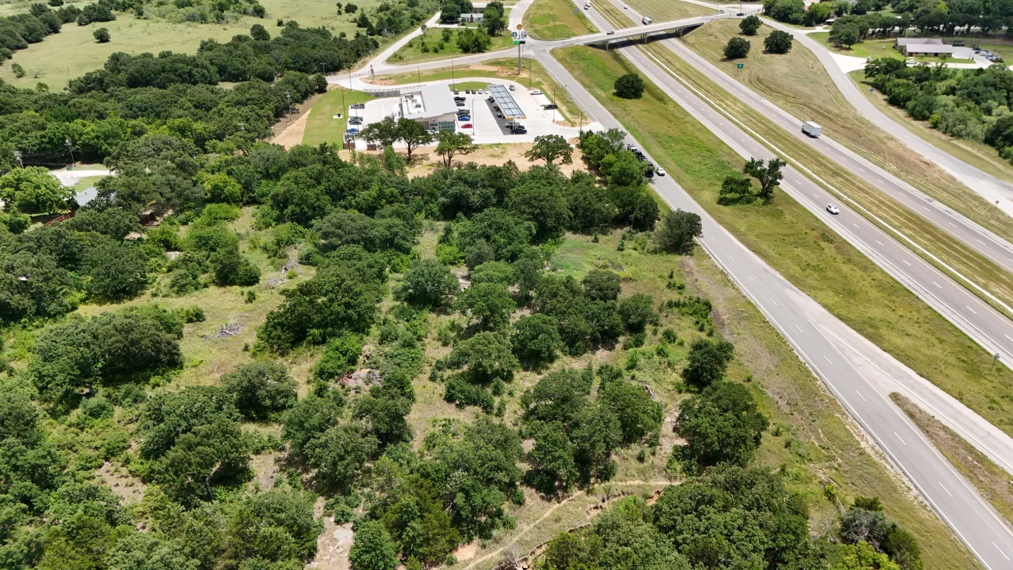 Expansive wooded acreage with mature tree coverage and natural landscape, adjoining direct highway access via adjacent thoroughfare