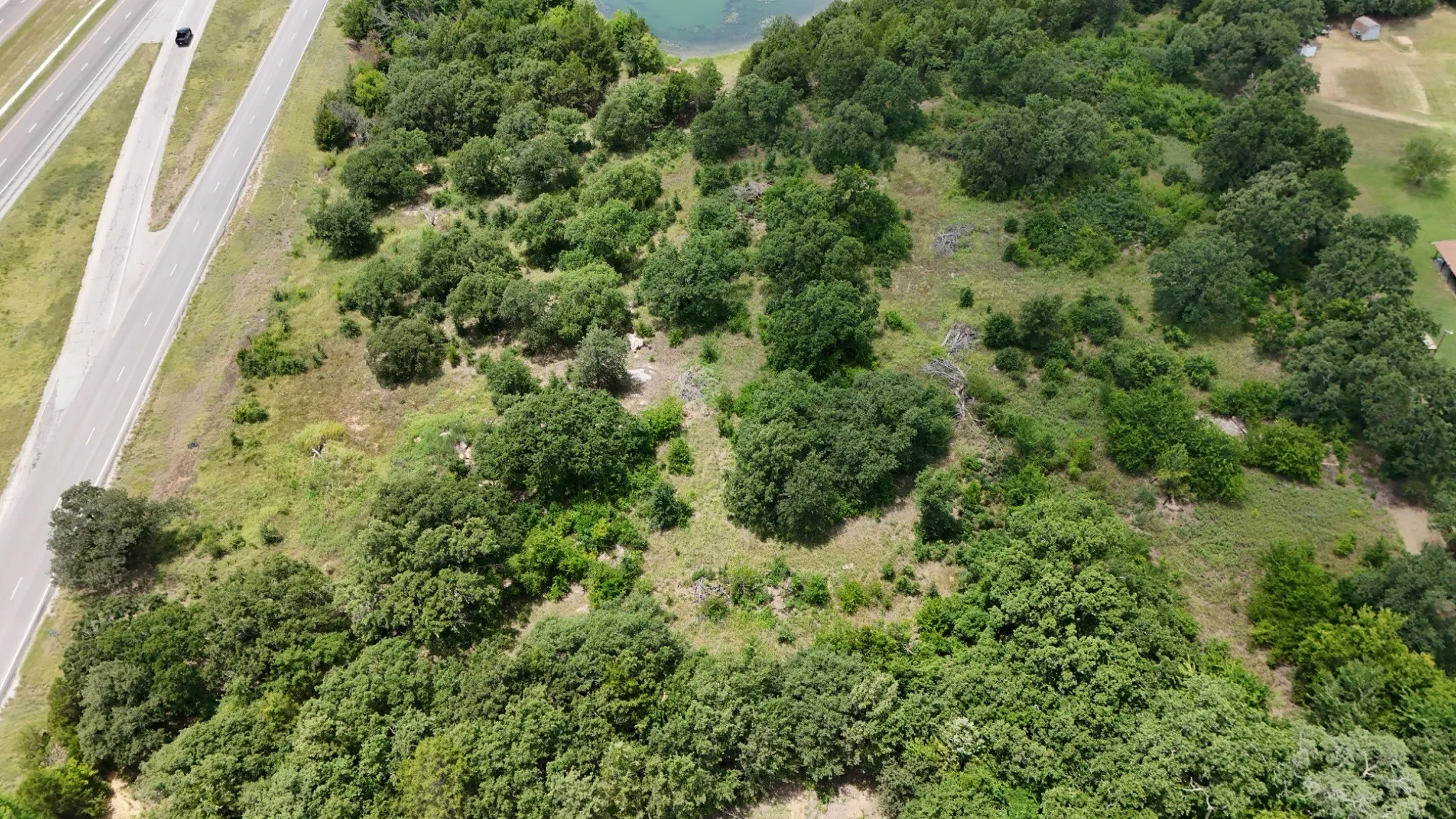 Expansive wooded lot featuring mature trees and a clear water body in the background