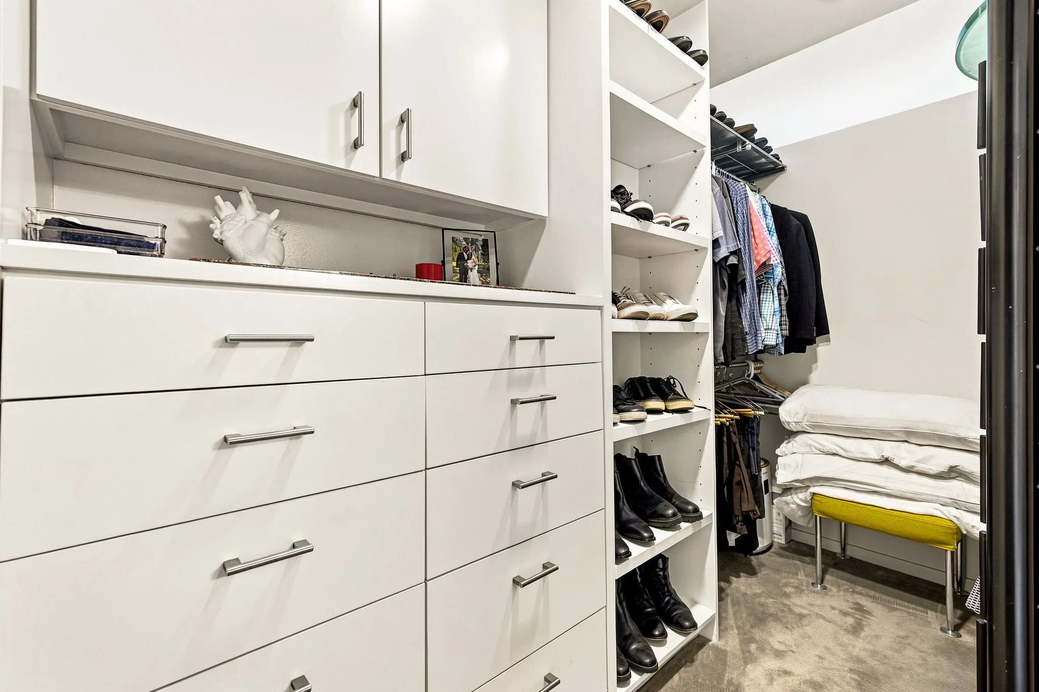 Custom closets with pull-out shelving and built-ins, featuring natural light that filters in from the adjacent bedroom.