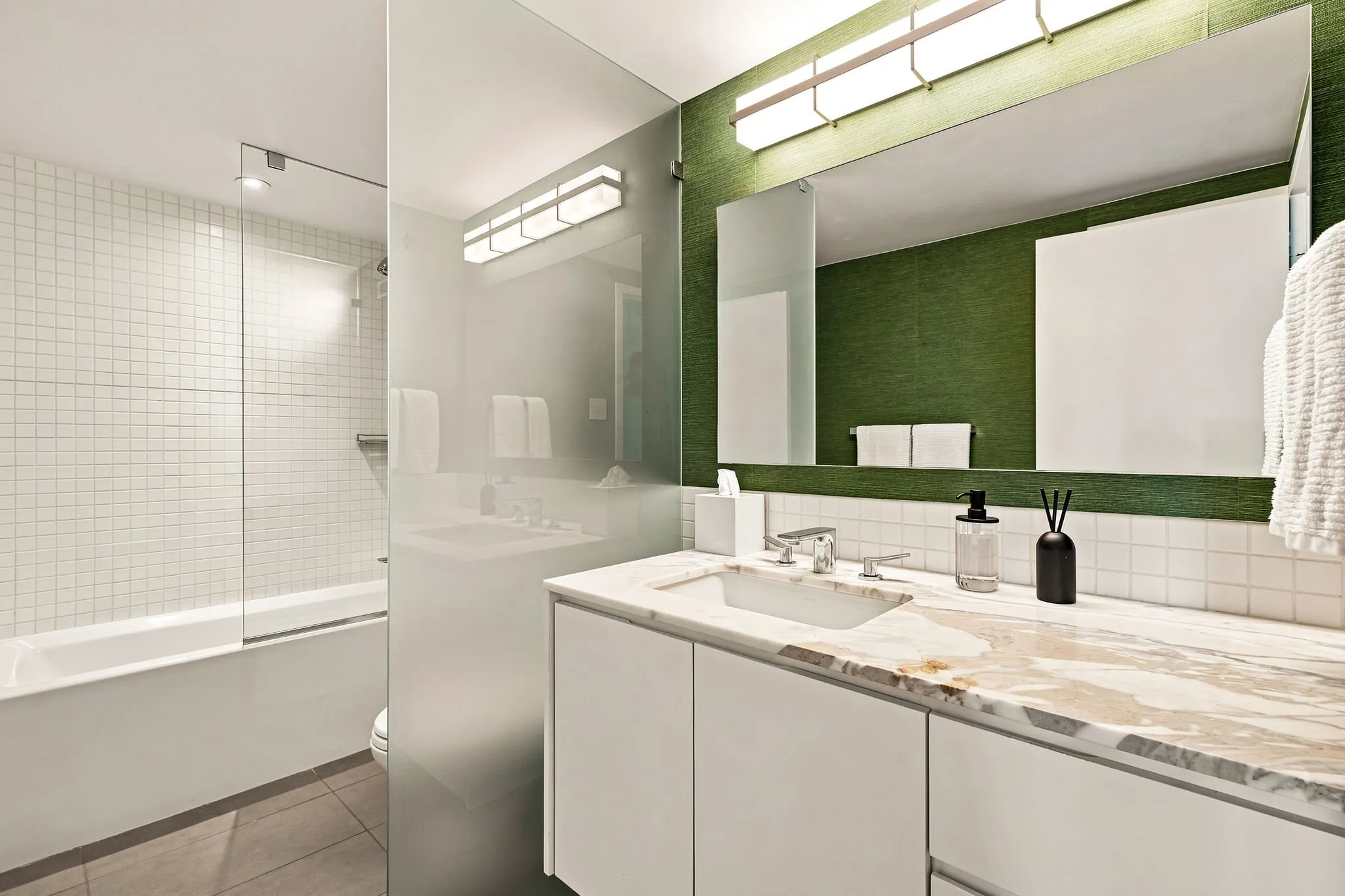 Marble countertops, grass cloth walls, and clean lines complete this updated bathroom. Conveniently located adjacent to the secondary bedroom and off the living room for guests.