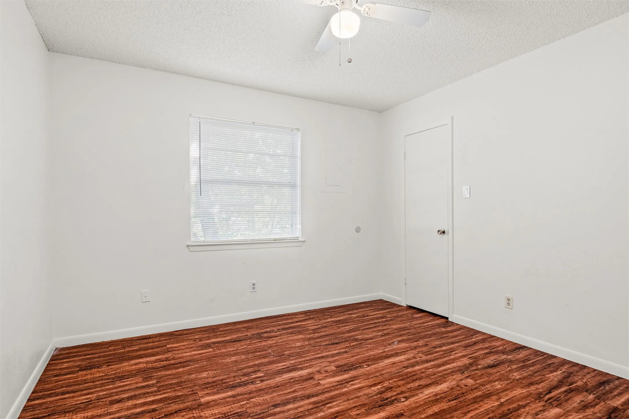 Fresh neutral walls, warm wood-look flooring, natural light, a ceiling fan, and closet storage make this bedroom ready to reflect your personal style—from a relaxing retreat to a productive home office.