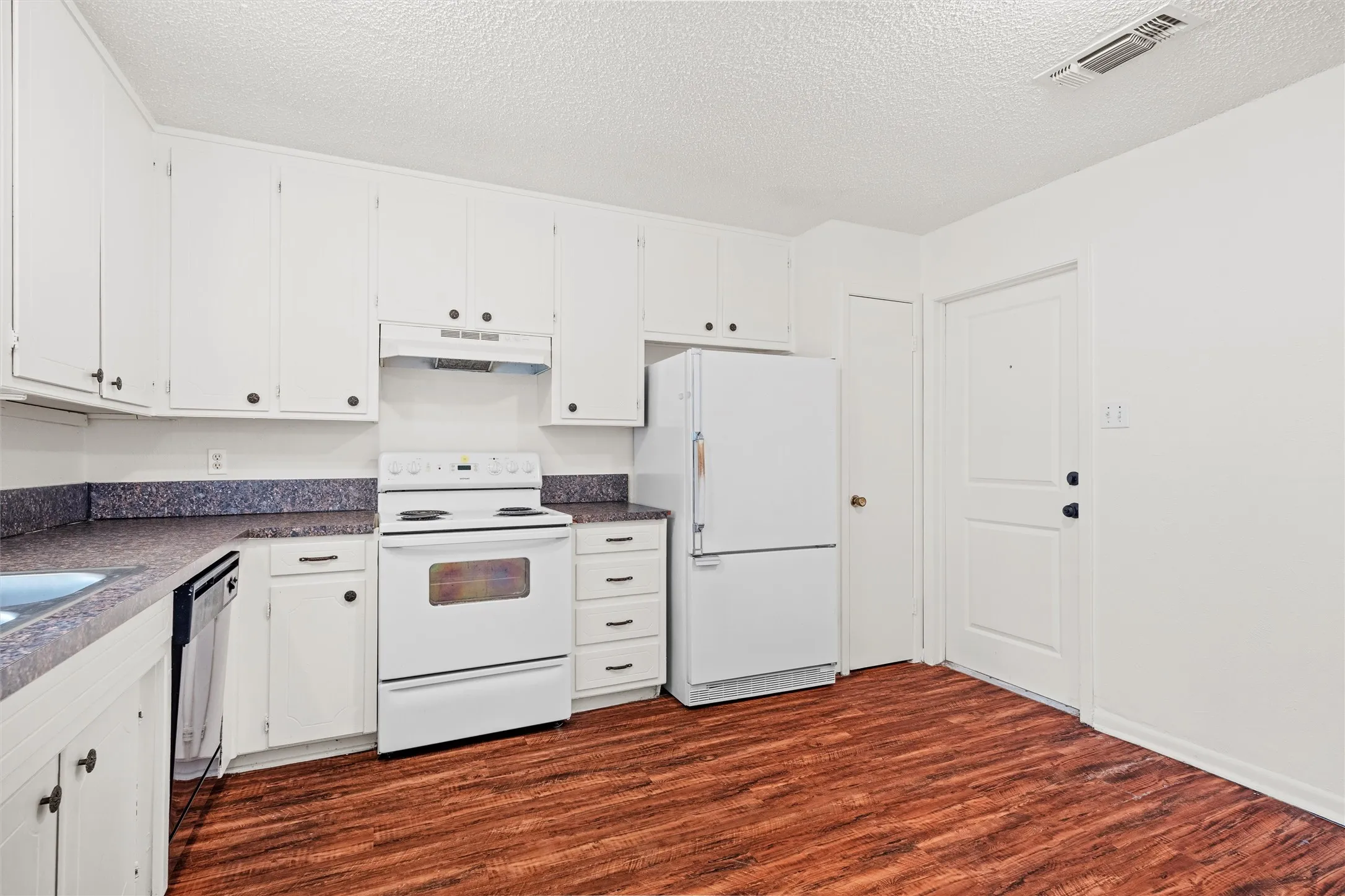 This cheerful kitchen offers abundant cabinet storage, multiple work surfaces, and a functional layout ready for weeknight meals, weekend baking, or your dream renovation.