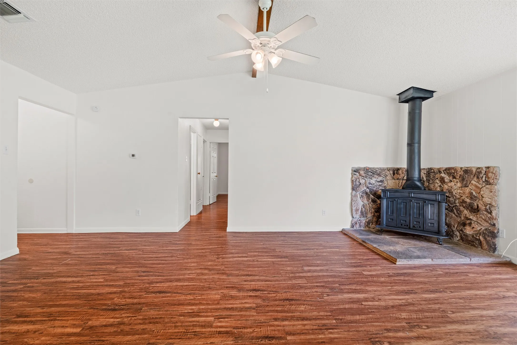 Imagine cooler nights gathered around this striking wood-burning stove, set against a rustic natural-stone surround. It’s not just a living room—it’s the place where memories are waiting to happen.