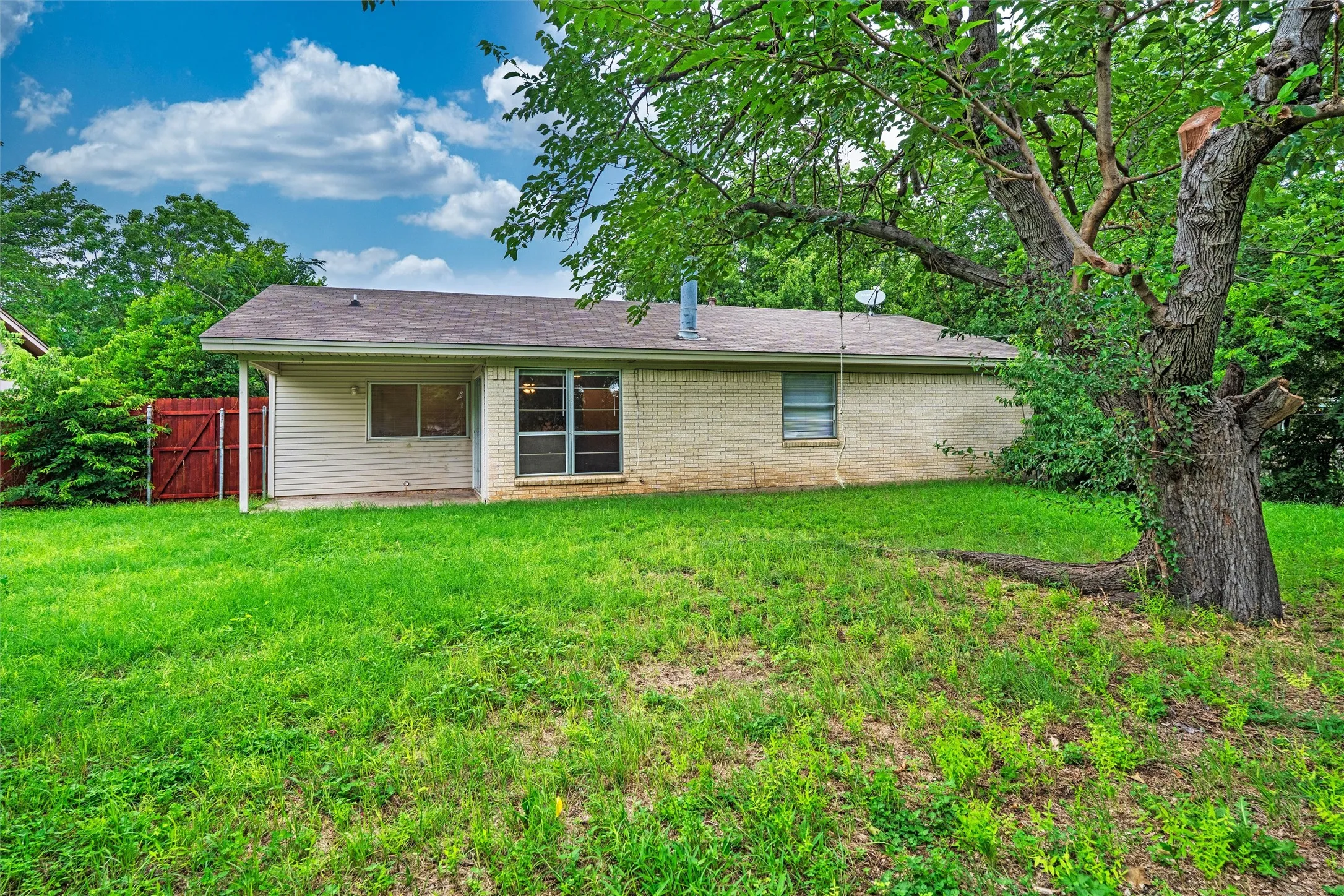 Mature shade trees, an expansive lawn, a covered patio, and plenty of open space make this backyard the perfect setting for weekend cookouts, family gatherings, pets, or peaceful evenings under the Texas sky.
