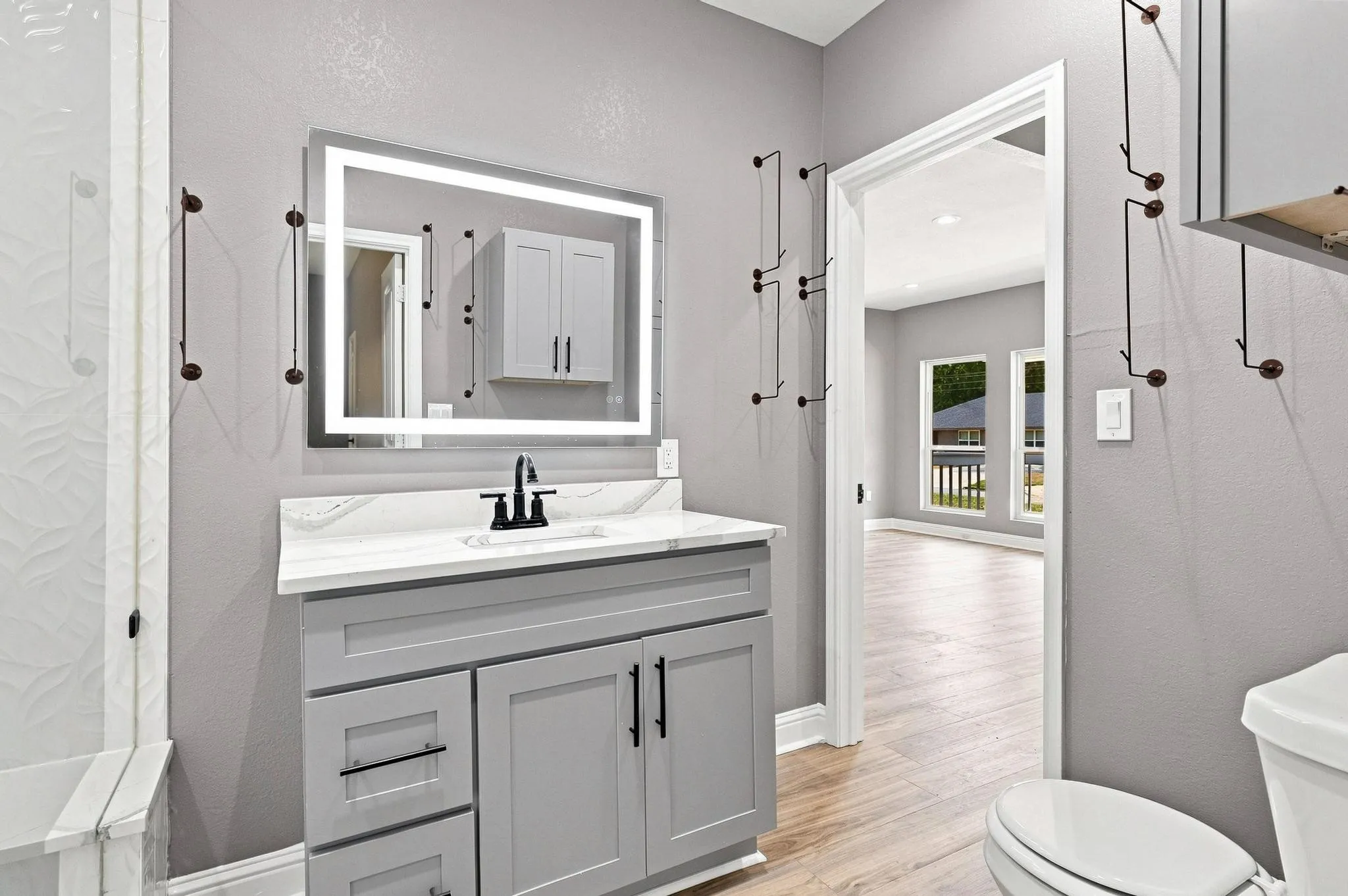 Floating vanity with a stone-finish countertop, undermount sink, and illuminated mirror