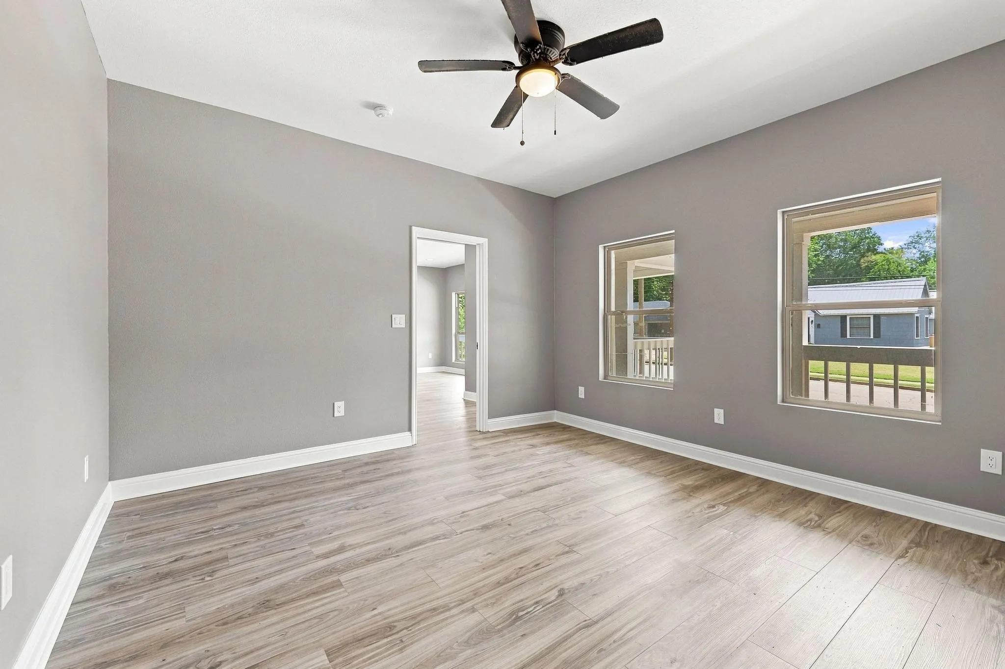 Vaulted ceiling with a ceiling fan, wood-finish flooring, and multiple windows