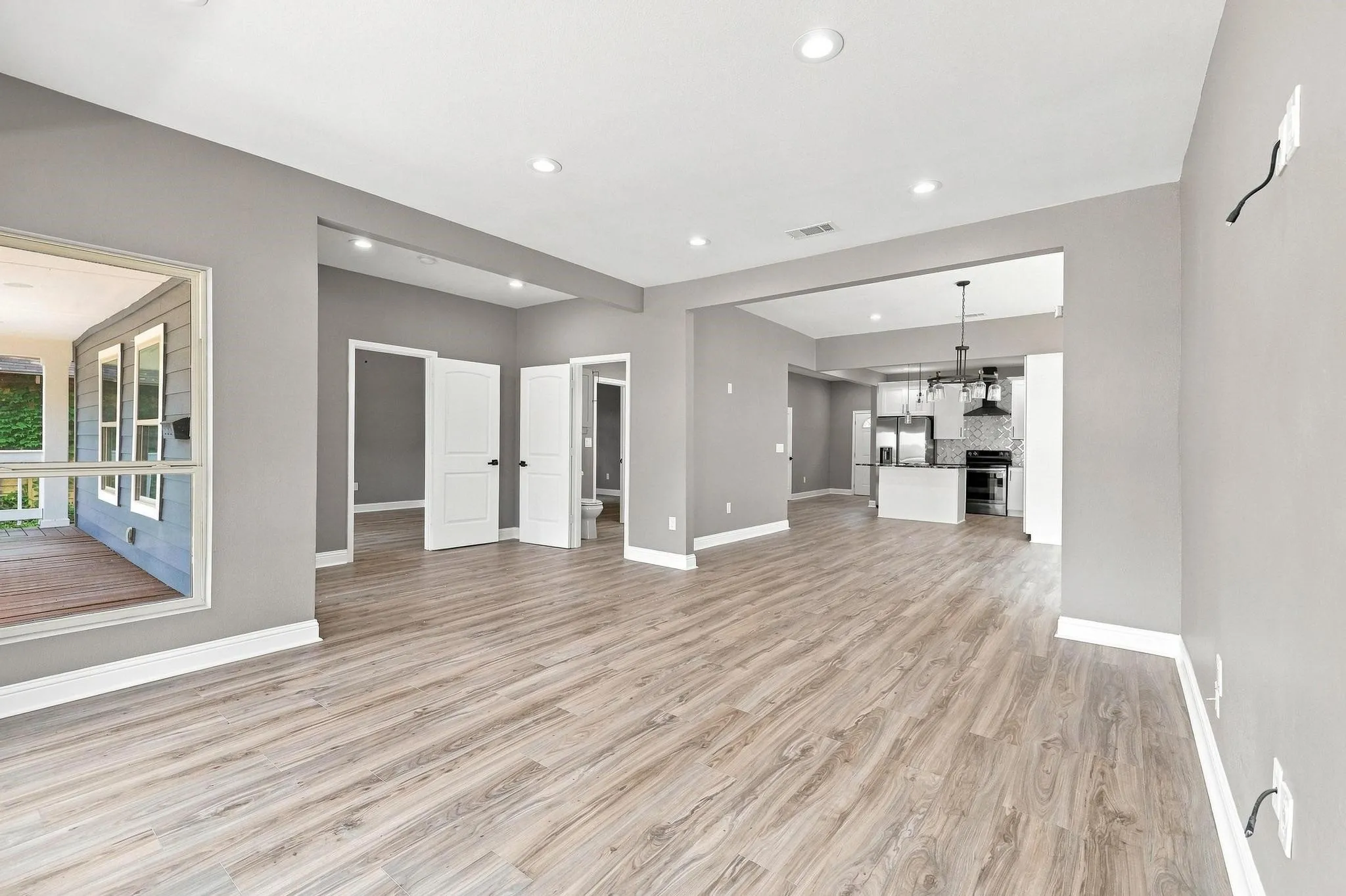 Wood-finish flooring throughout, featuring a recessed lighting design and crisp white trim