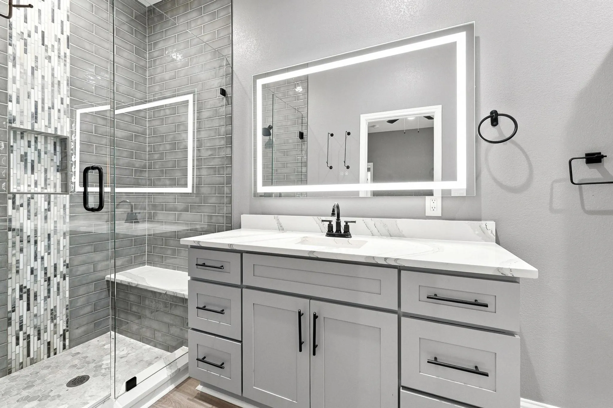Glass-enclosed shower with subway tile surround and integrated bench