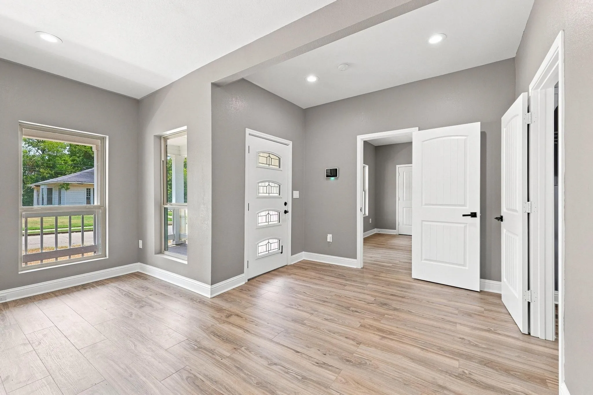 Spacious entry area with wood-finish flooring, recessed lighting, and a decorative glass-paneled entry door