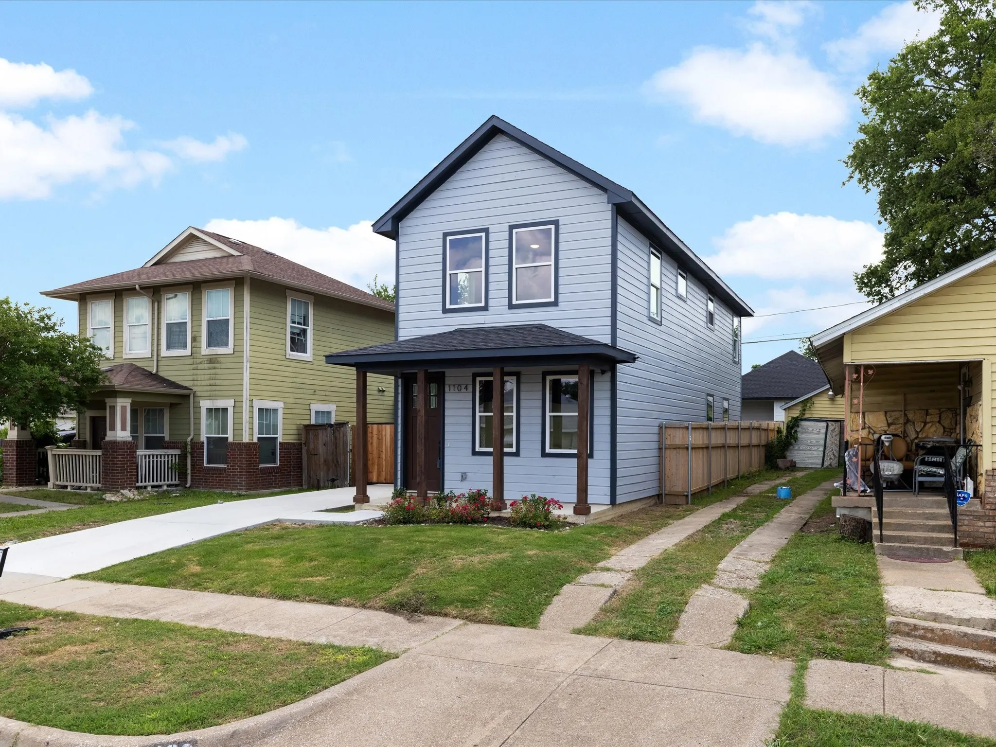 Modern two-story home featuring light blue fiber cement siding with contrasting dark trim, a peaked roofline, and a welcoming front entrance with dual entry doors