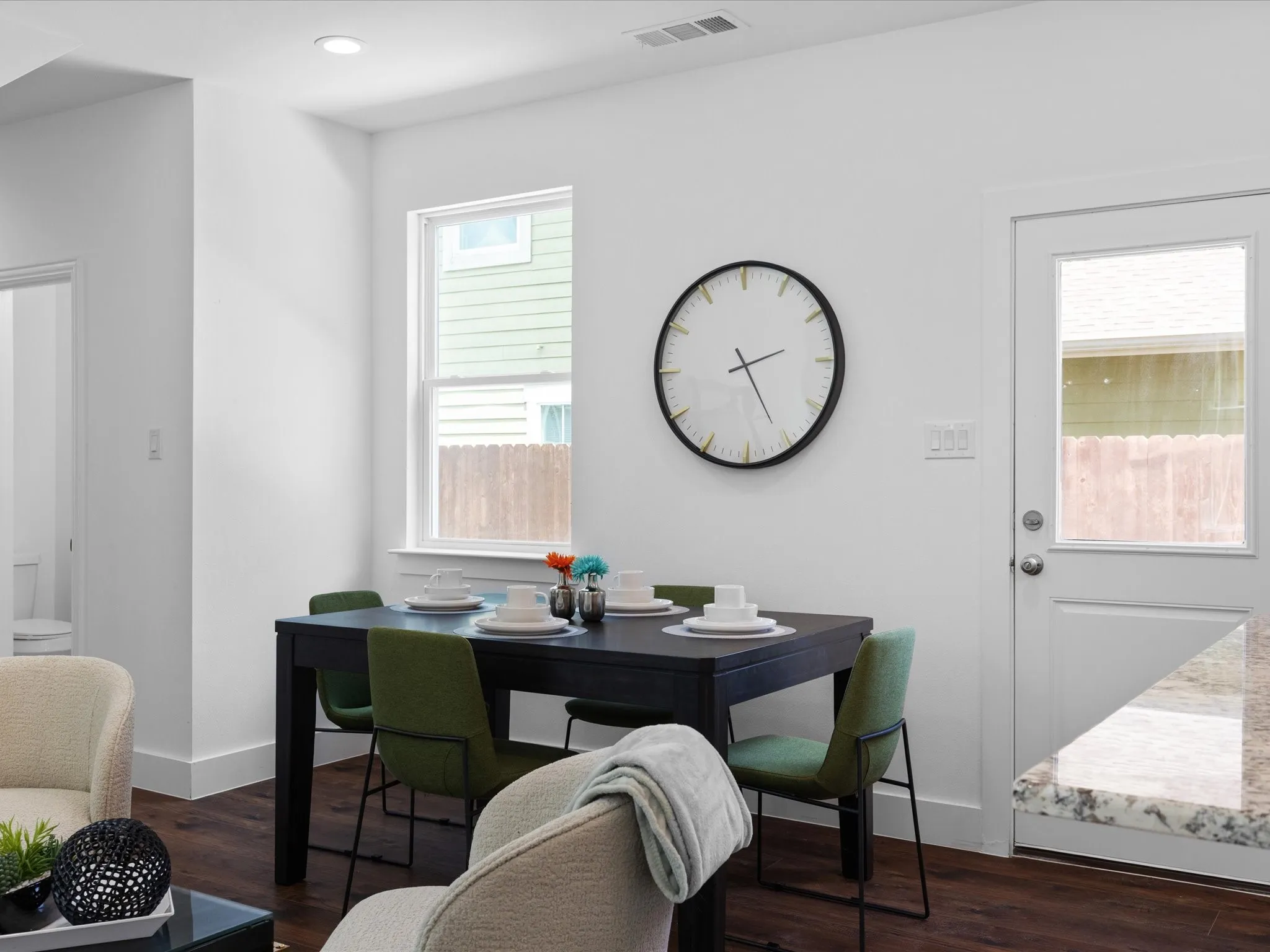 Dining area featuring wood-finish flooring, a white trim window, a white trim exterior door with integrated glass, recessed lighting, and a granite countertop visible in the foreground