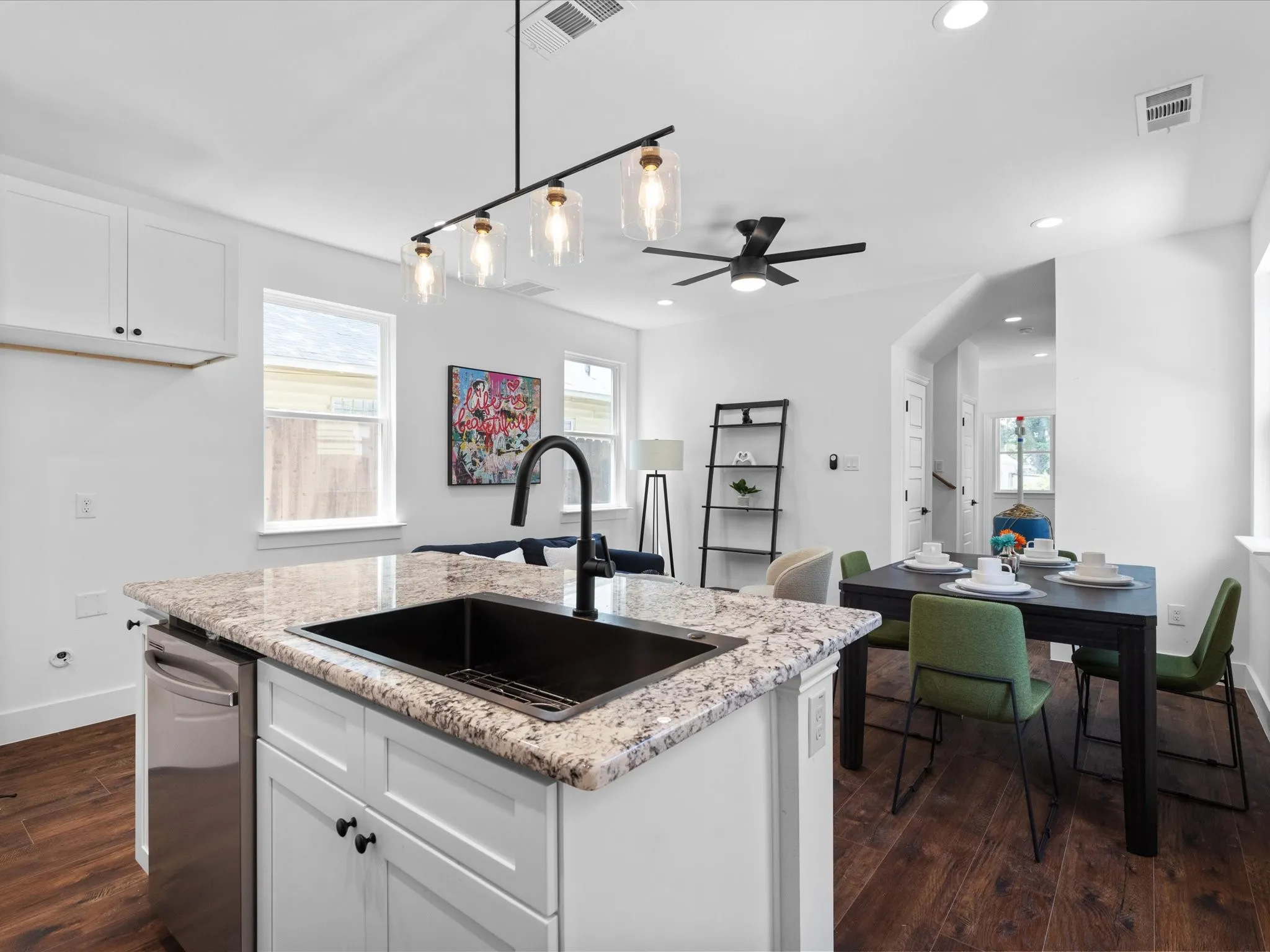 Kitchen island featuring a black sink, gooseneck faucet, and light granite countertop