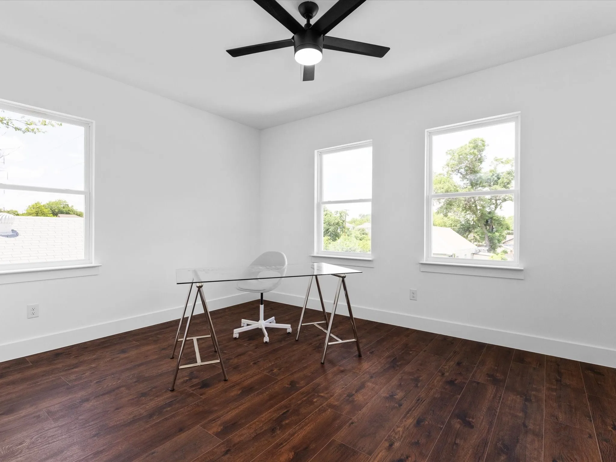Bright interior space featuring wood-finish flooring, white walls, and multiple windows