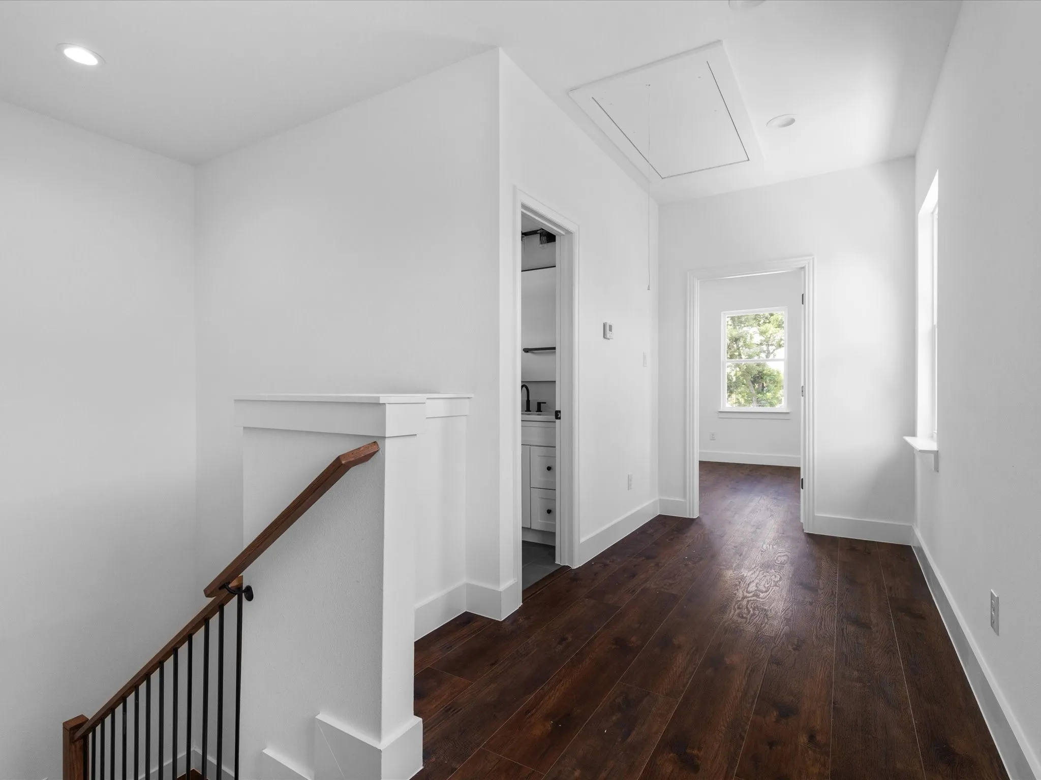 Hallway featuring dark wood-finish flooring, recessed lighting, and a white trim package