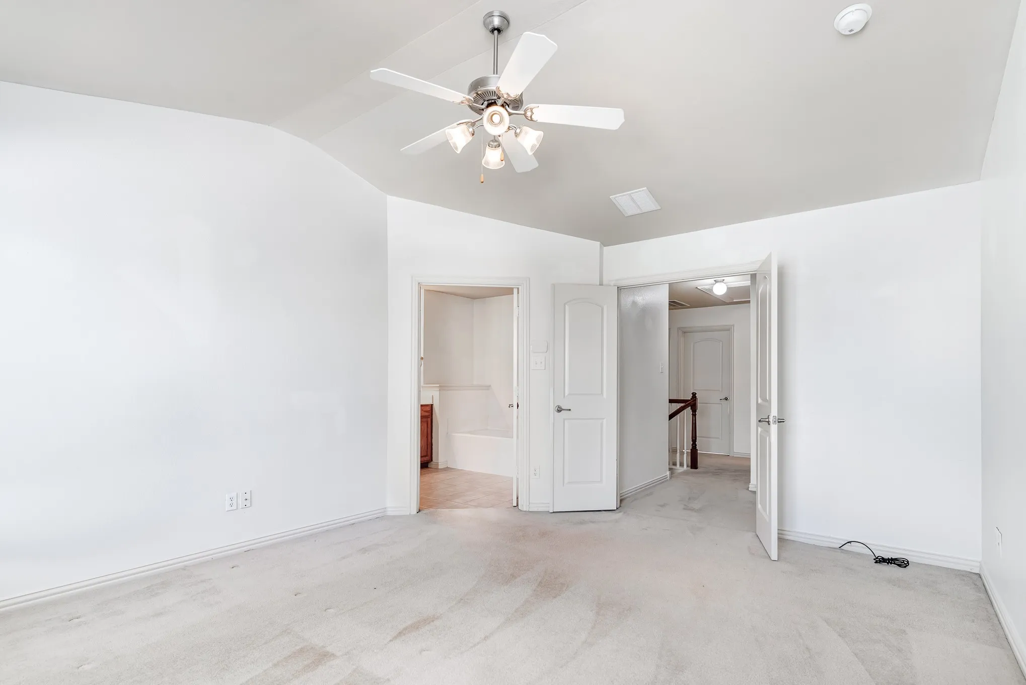 Unfurnished bedroom with ensuite bath, ceiling fan, lofted ceiling, and light carpet