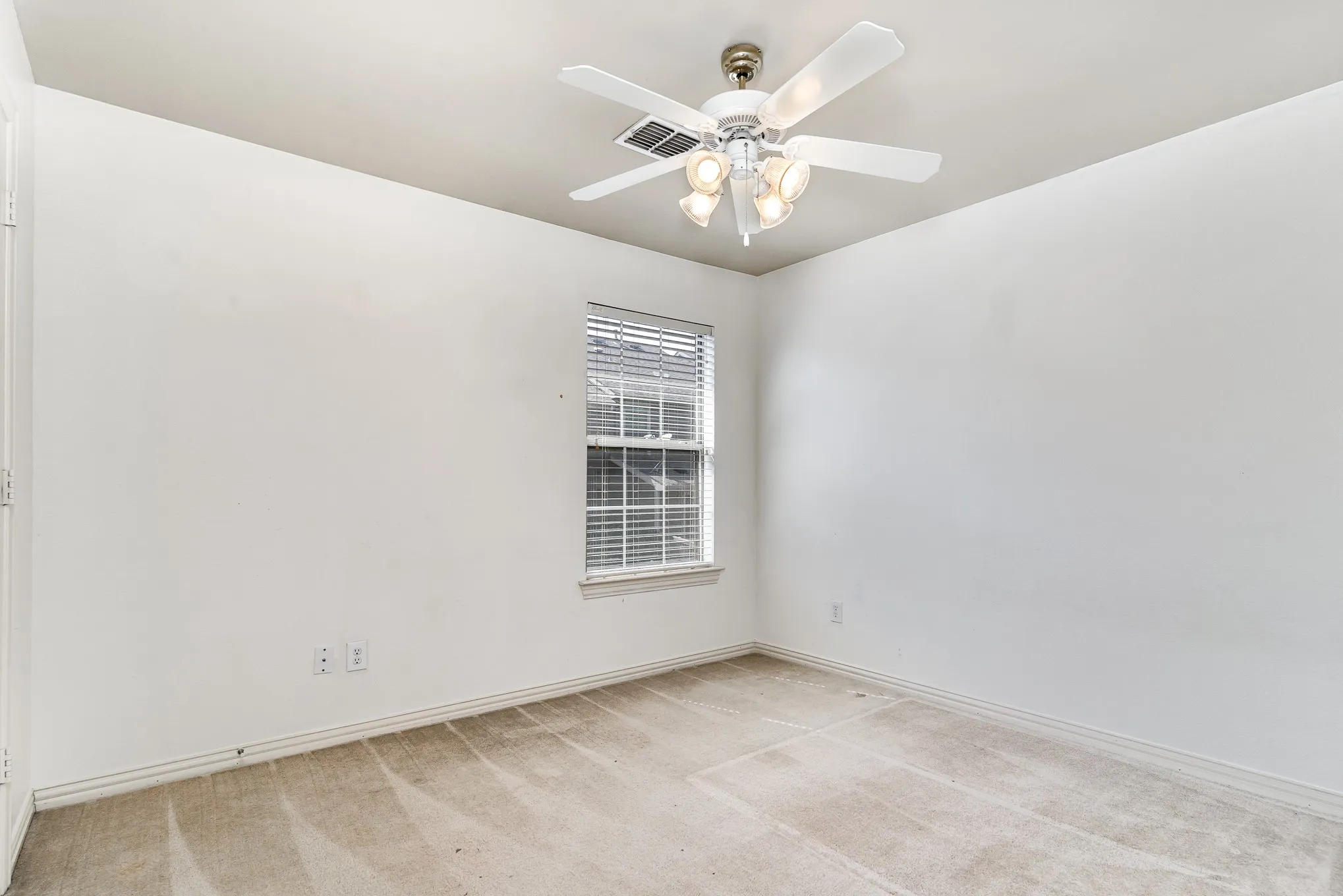 Empty room with light colored carpet and ceiling fan