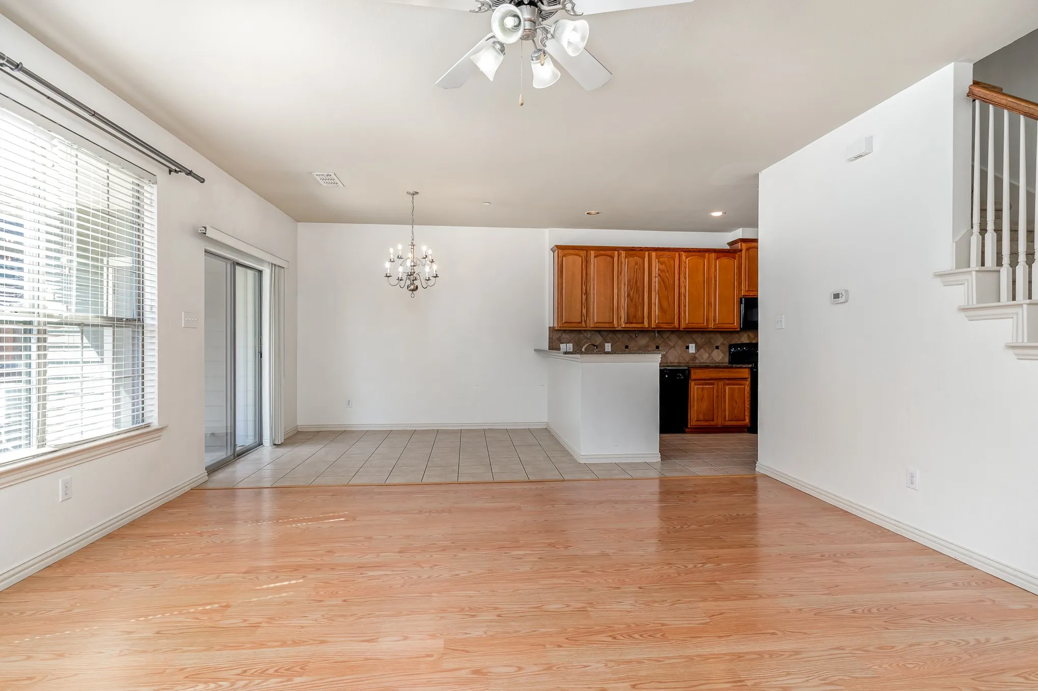 Unfurnished living room featuring a healthy amount of sunlight, light hardwood / wood-style flooring, and ceiling fan with notable chandelier