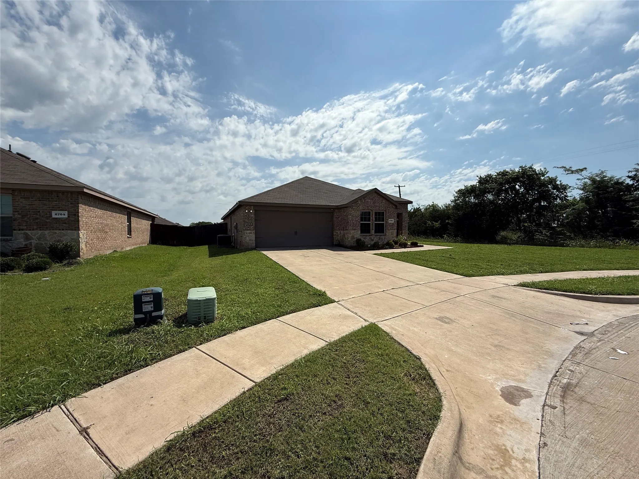 Single-story residence featuring a brick and stone facade, an attached garage, and a concrete driveway