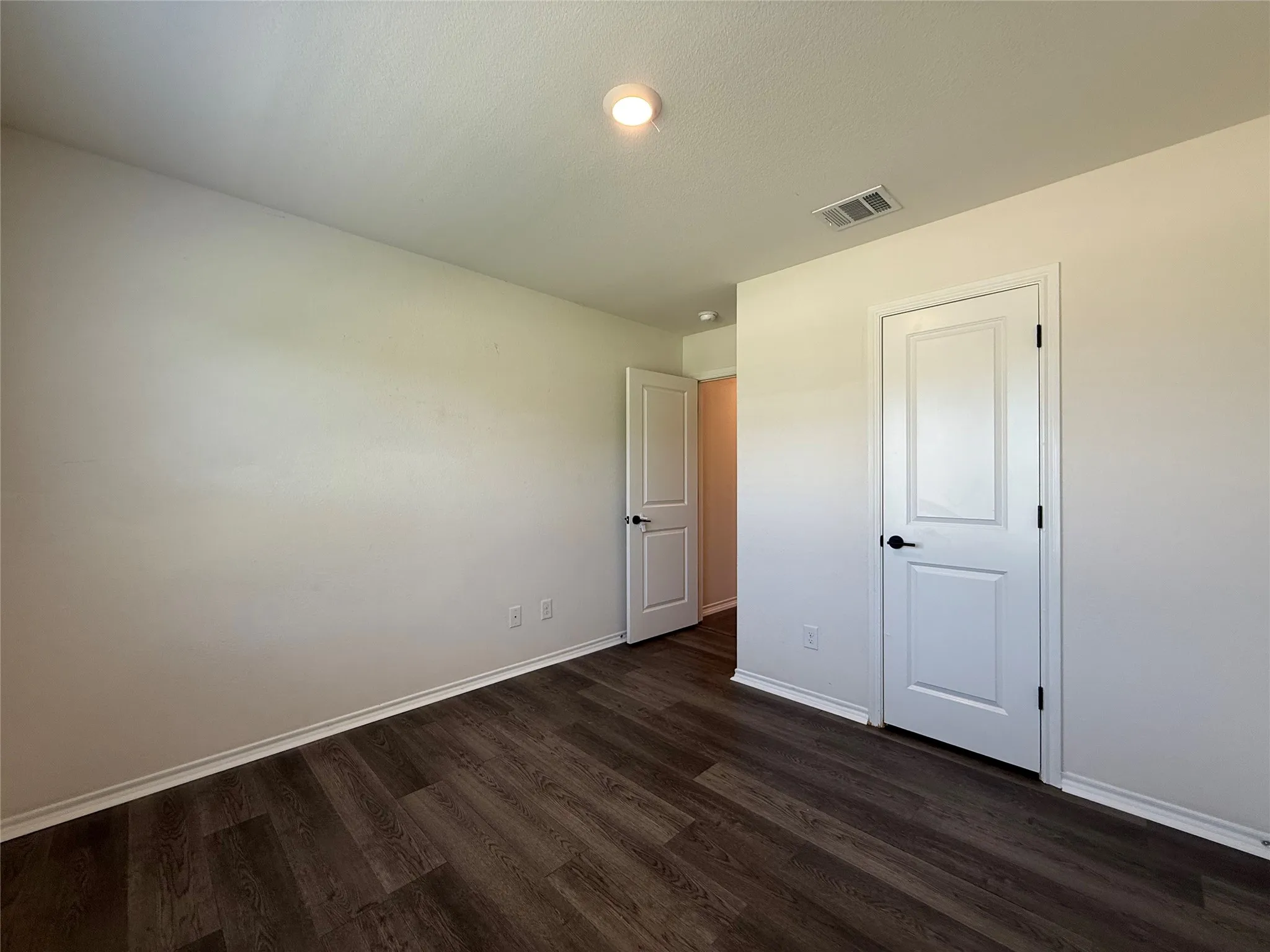 Room featuring wood-finish flooring, white baseboards, and neutral wall paint