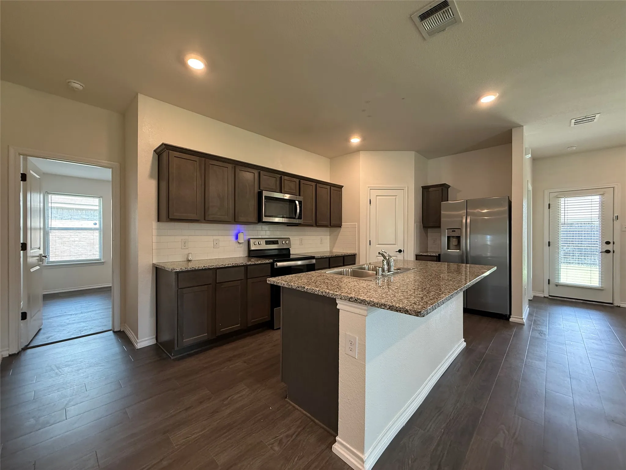 Kitchen featuring wood-finish flooring, dark wood cabinetry, and stainless steel appliances