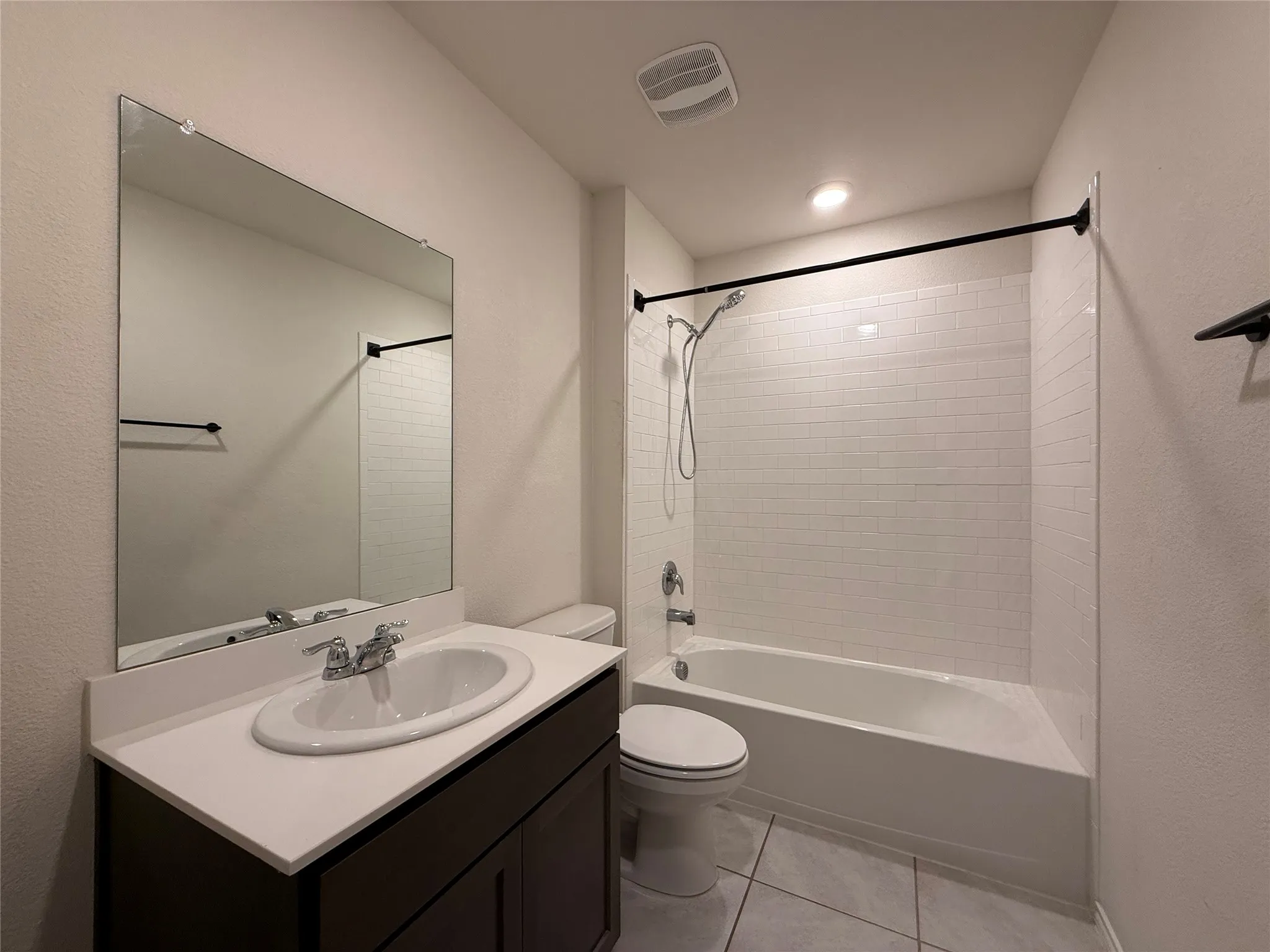 Bathroom featuring a dark wood-finish vanity with an oval undermount sink, a white countertop, and a large wall-mounted mirror