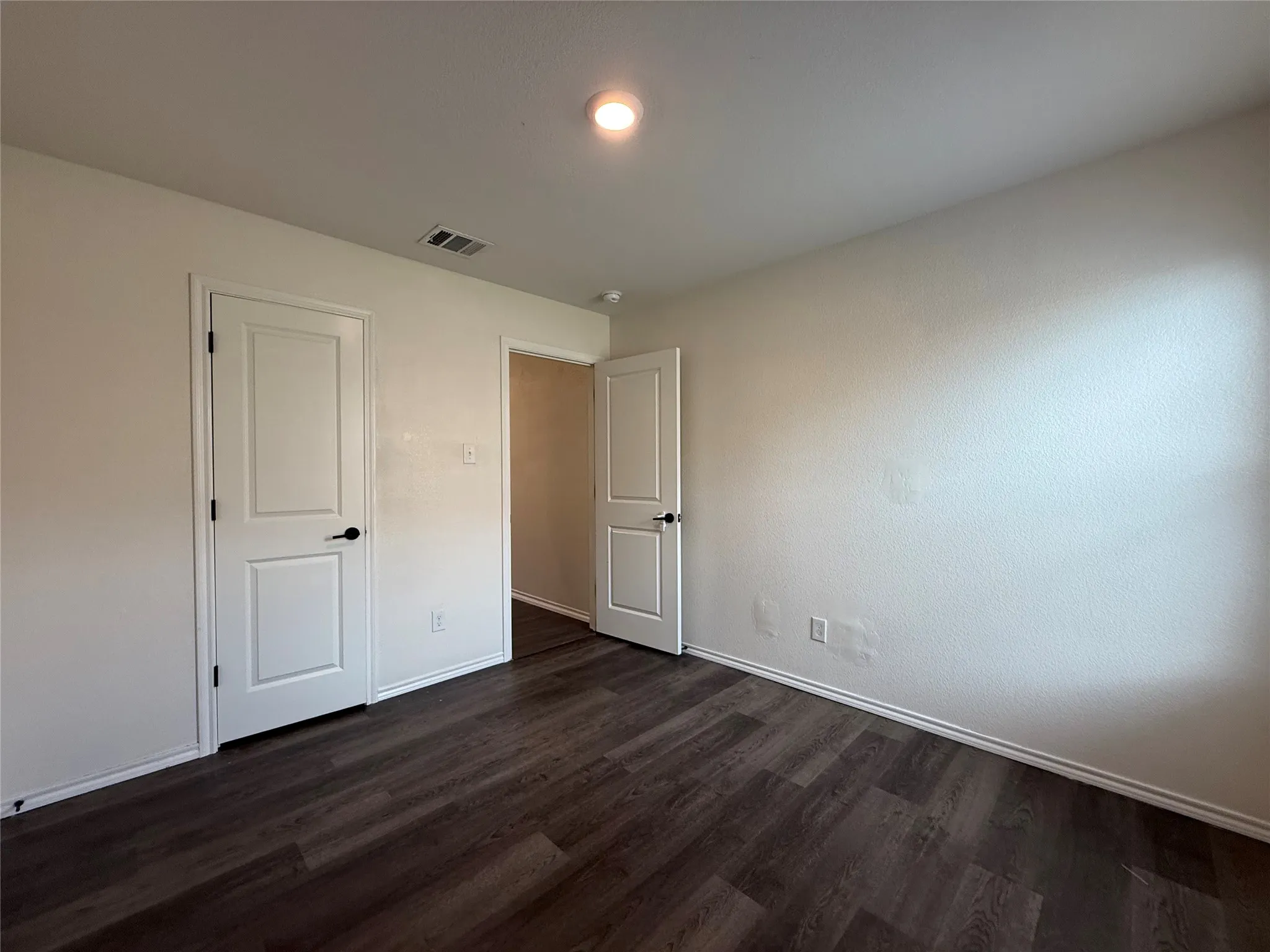 Room featuring wood-finish flooring, white baseboards, and neutral wall paint