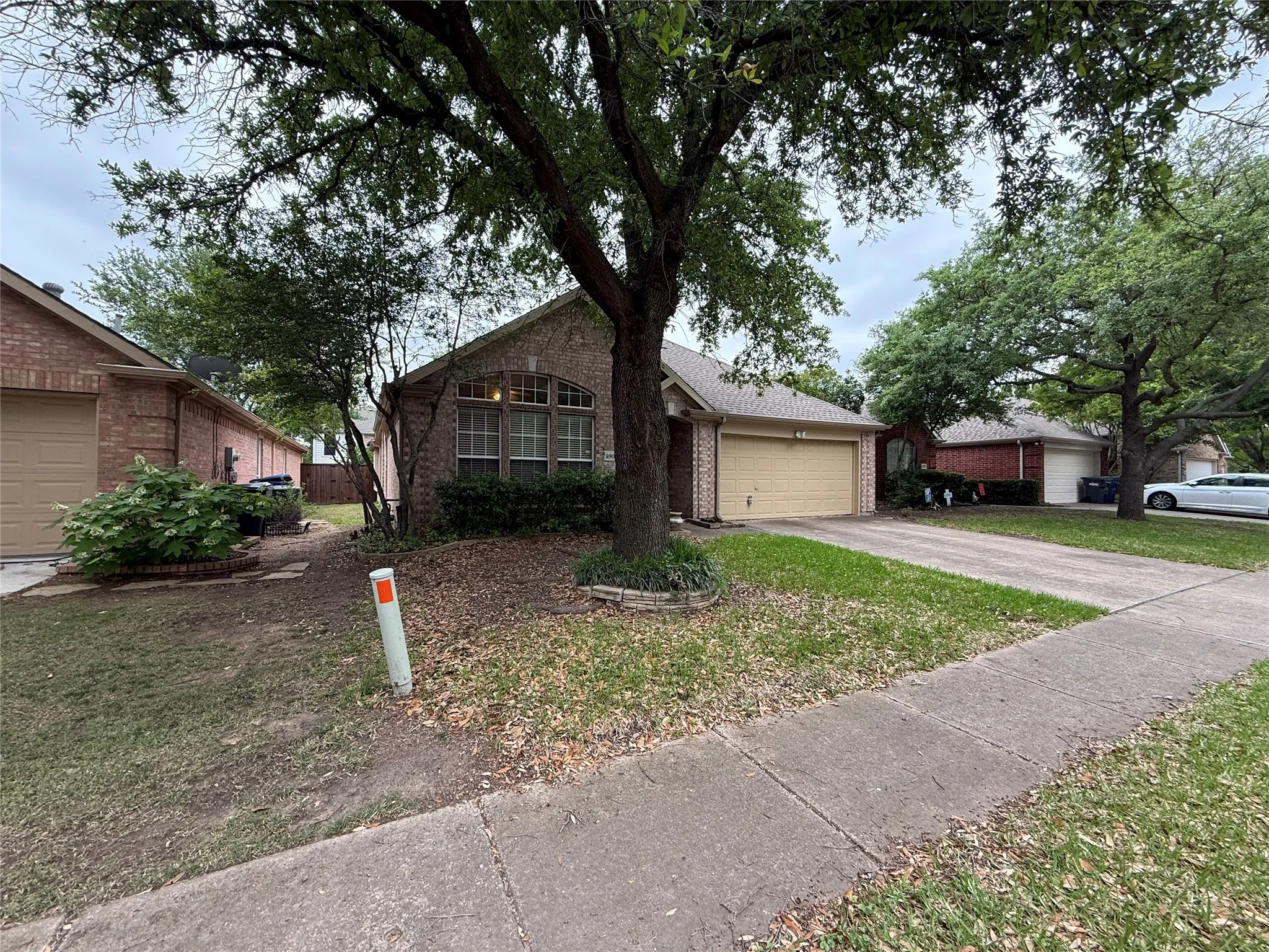 Brick exterior featuring an arched window, a two-car garage, and a concrete driveway