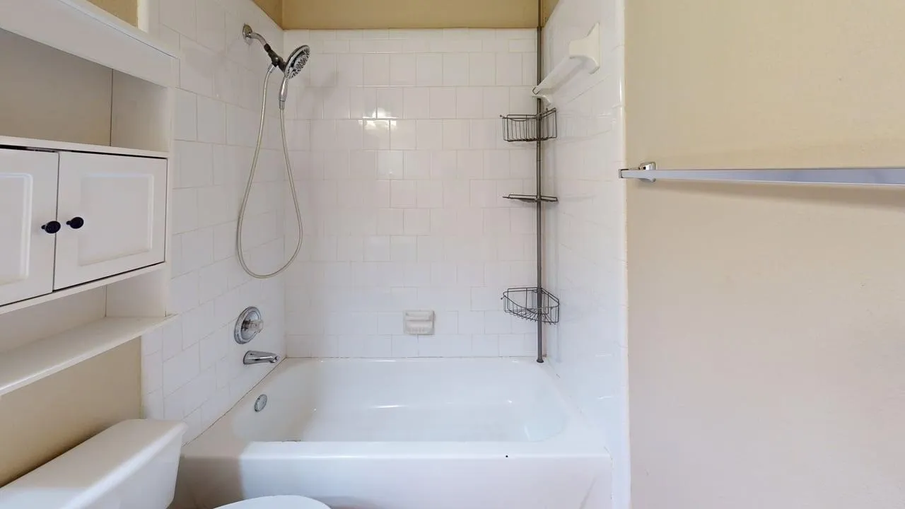 Bathtub with white subway tile surround, chrome fixtures, and a wall-mounted showerhead
