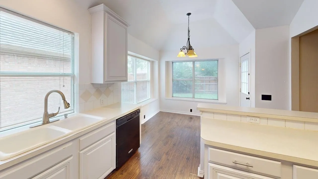 Kitchen featuring a dual basin sink with a gooseneck faucet, white cabinetry, and a black dishwasher