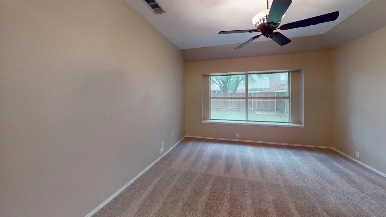 Spacious bedroom with ceiling fan, large window with natural light, and wood-finish flooring throughout