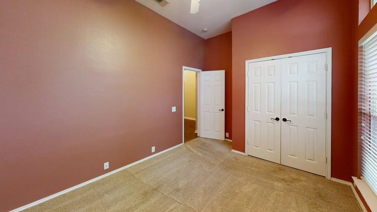 Carpeted room featuring high ceilings, a double-door closet, a window with blinds, and white trim