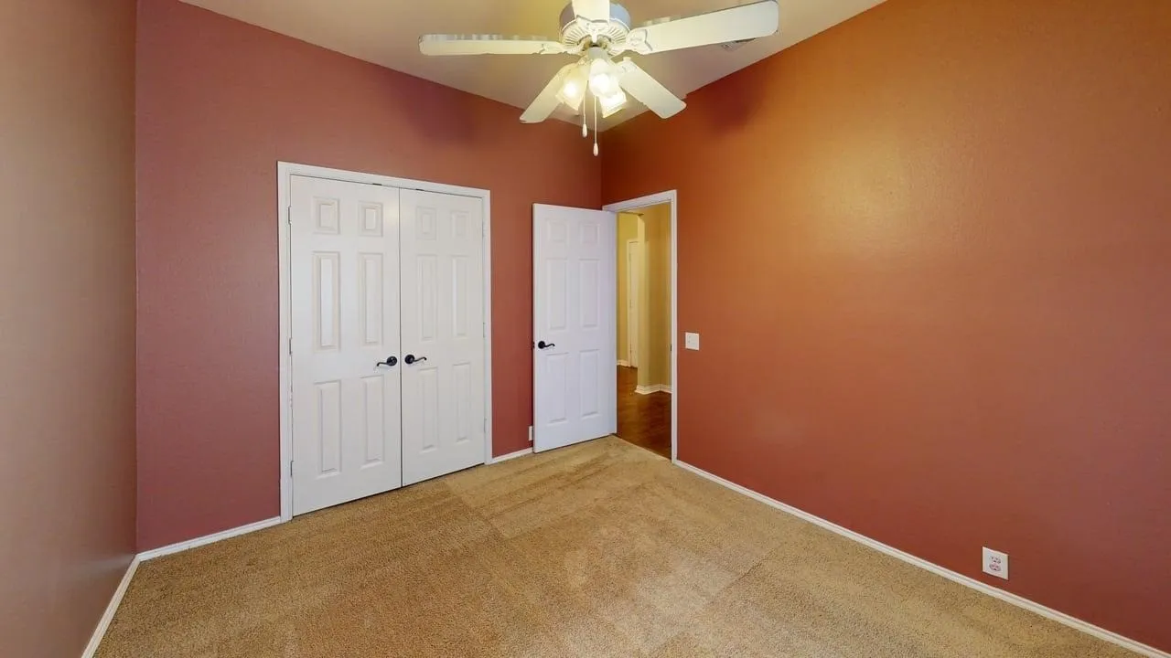 Carpeted room with vaulted ceiling and ceiling fan