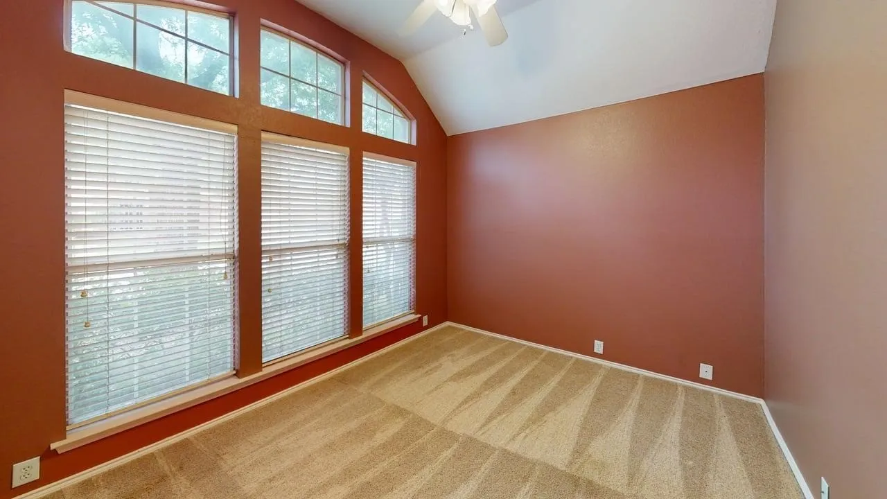 Carpeted room with vaulted ceilings and a ceiling fan