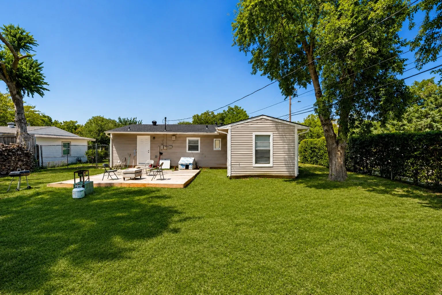 Expansive backyard featuring a manicured lawn, a spacious wooden deck, and a detached storage shed