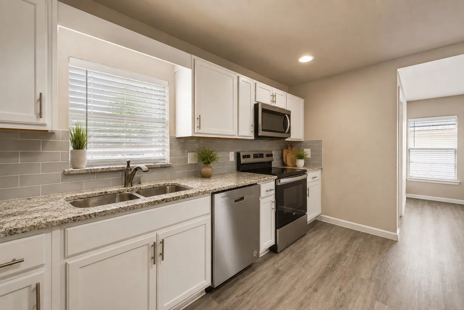Modern kitchen featuring white cabinetry, stainless steel appliances, speckled stone countertops, and gray subway tile backsplash