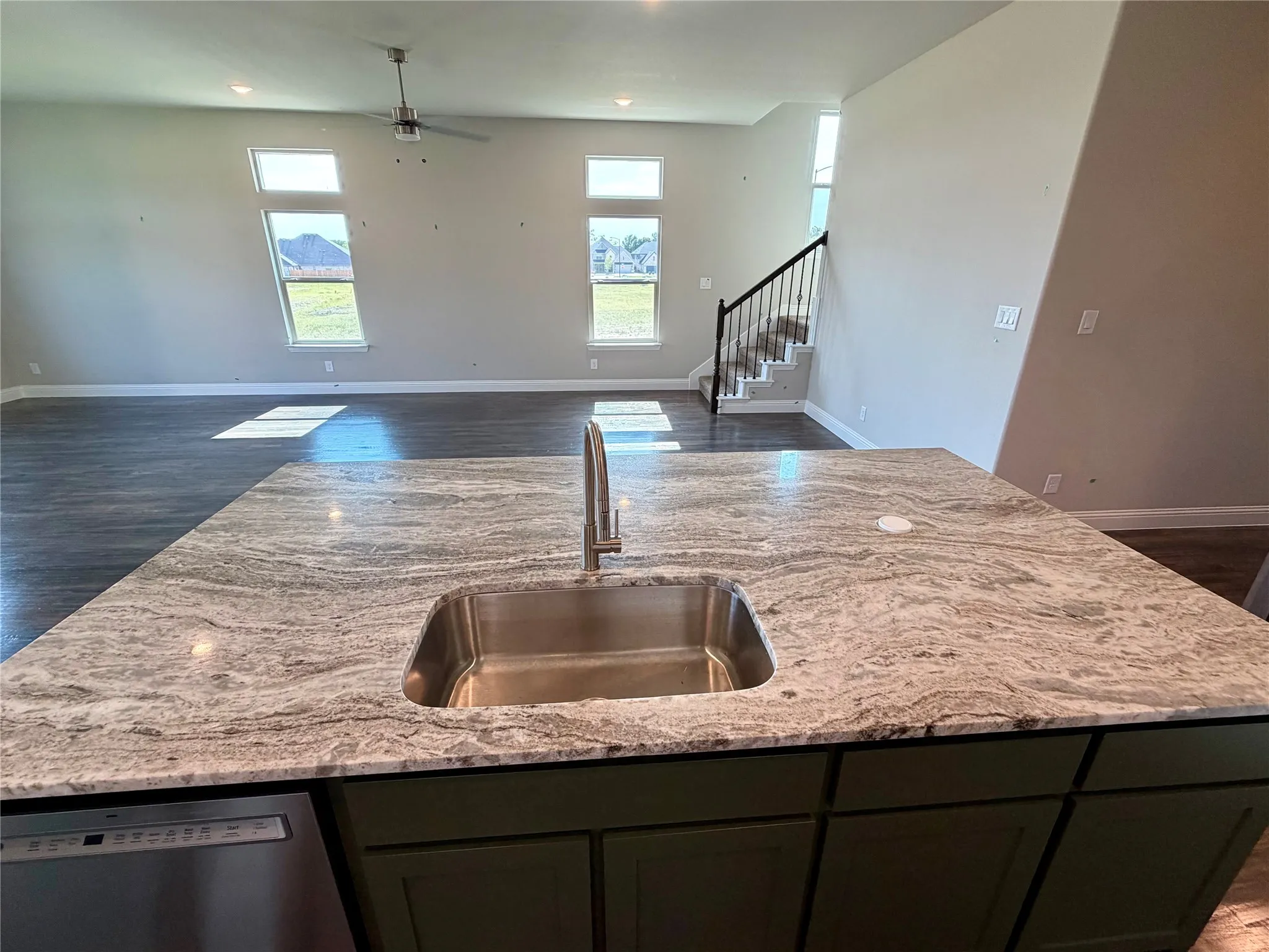 View from kitchen island towards family room. This home has pop up outlet in island & underount single basin sink and extendable faucet..