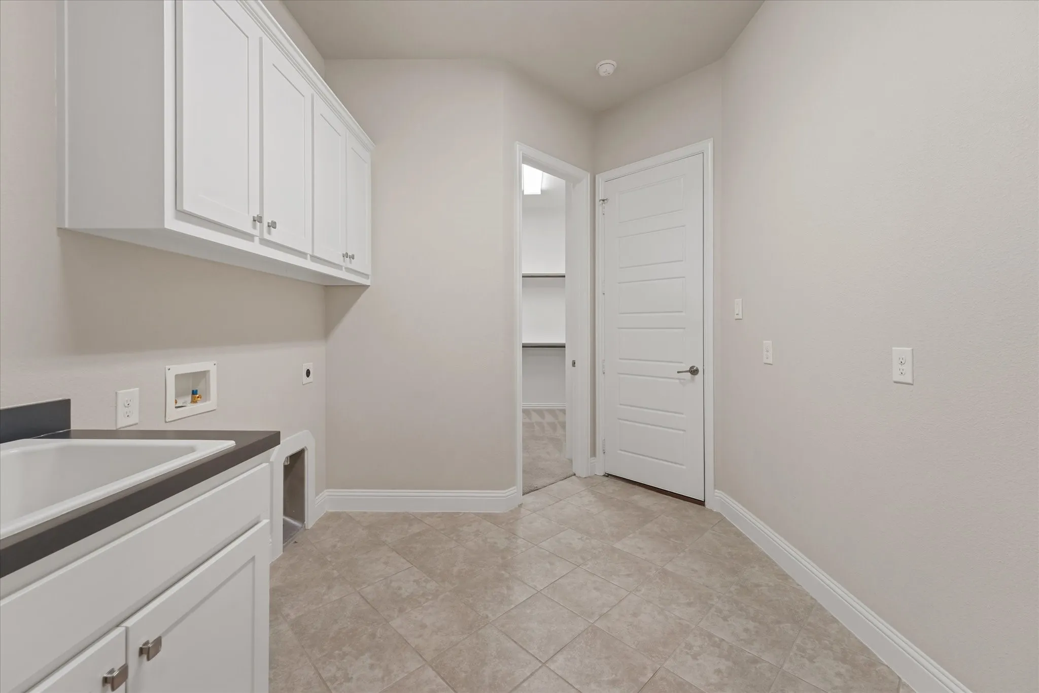 laundry room features tons of space, full size hook ups, a sink, and storage cabinets. There is a Tesla charger in the one car garage off this room.