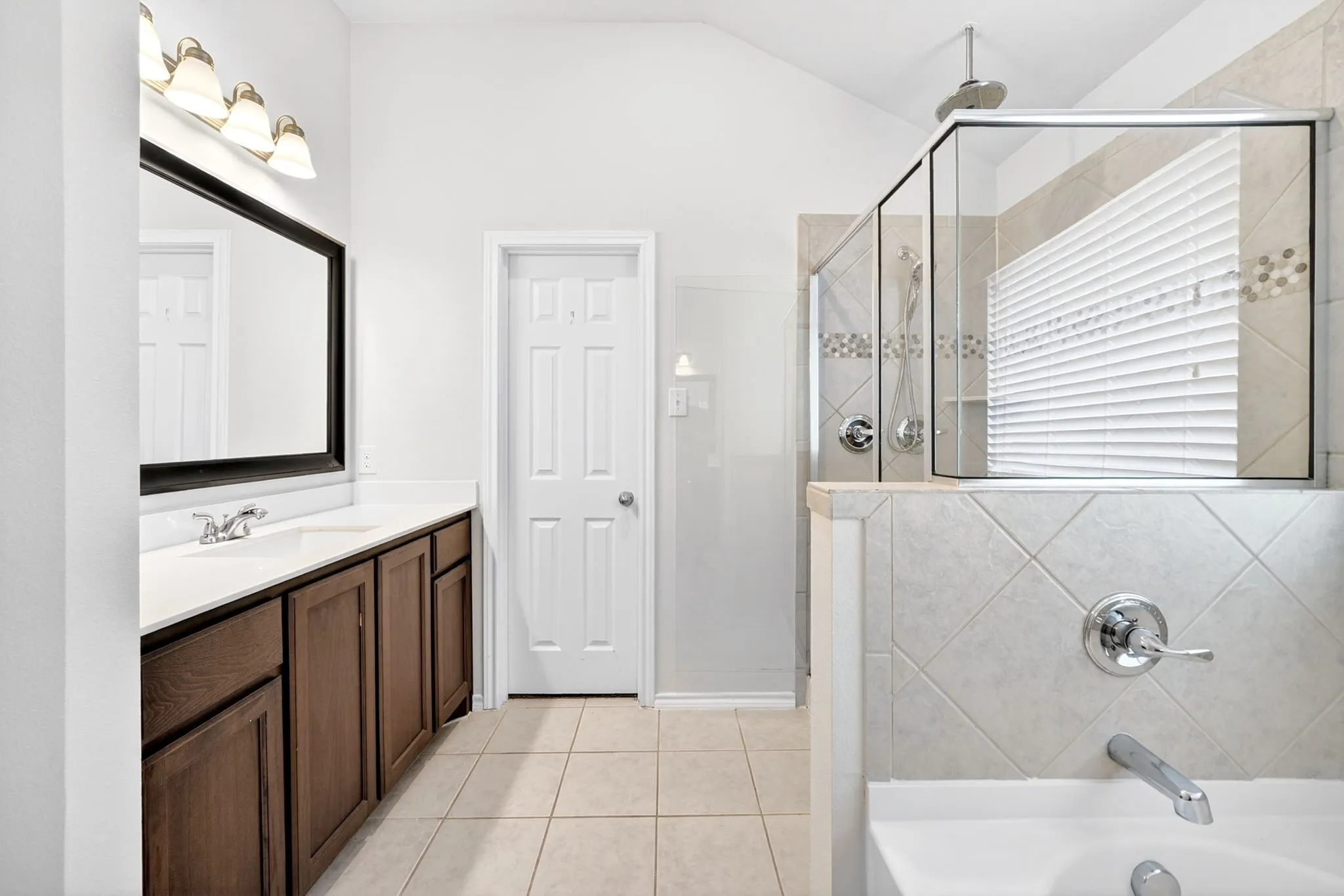 Spa-inspired primary bathroom featuring a dual-sink vanity with wood cabinetry, white quartz countertops, and polished chrome fixtures