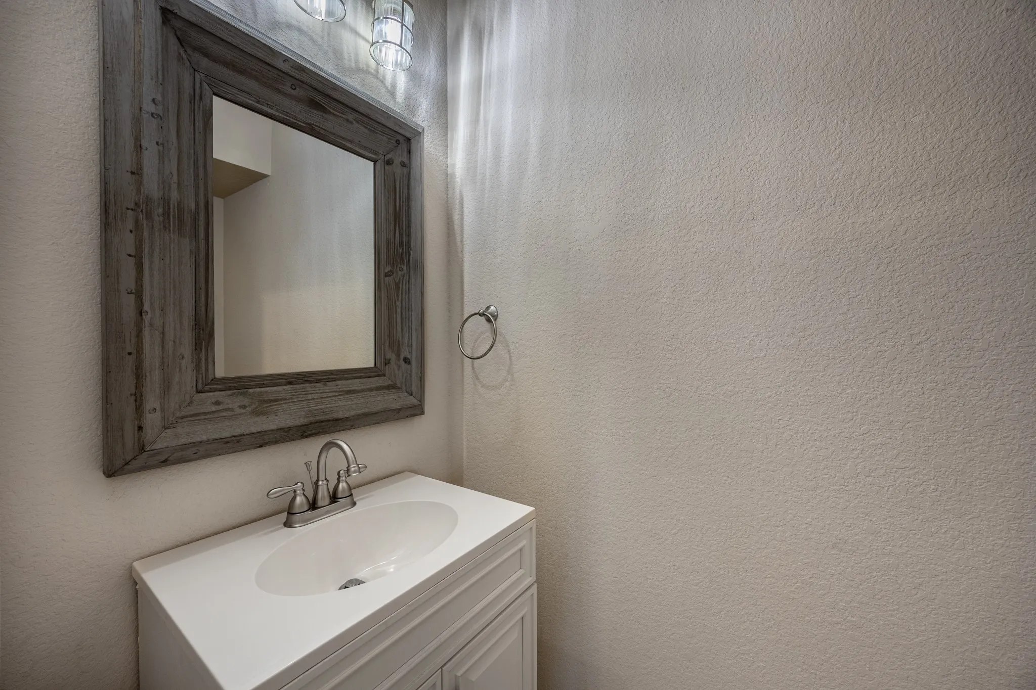 Half Bathroom
Vanity with a white countertop and integrated sink, brushed nickel faucet, and a large wood-framed mirror
