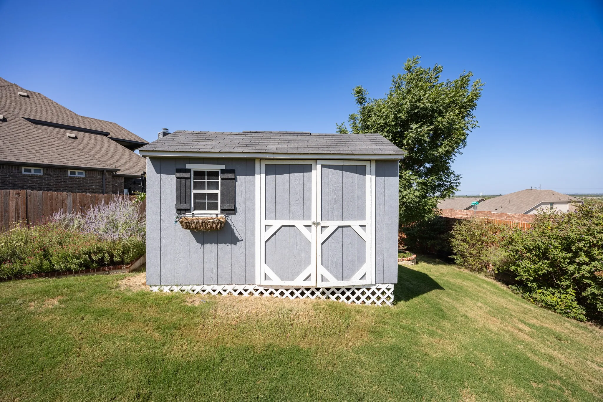 Freestanding shed with light blue siding, white trim, and a shingled roof