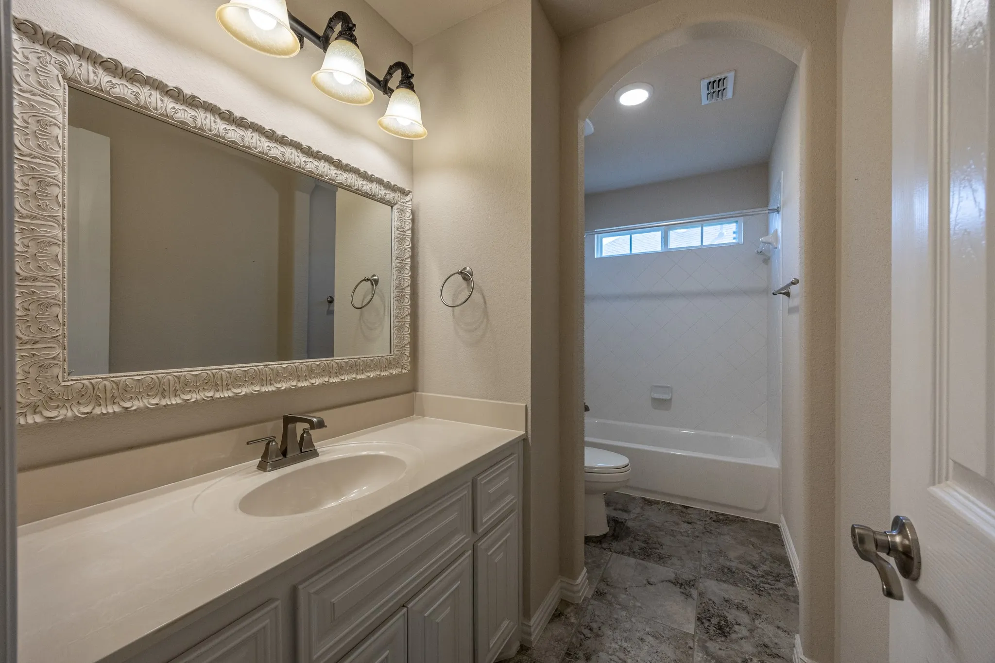 Bathroom vanity featuring an ornate framed mirror, a single basin sink, and ample storage cabinetry