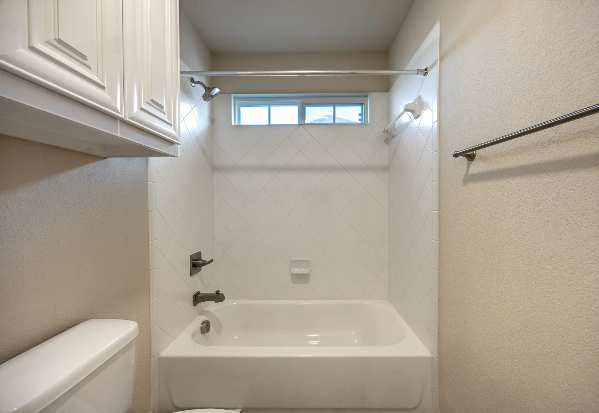 Tub and shower combination featuring white subway tile surround and dark bronze fixtures