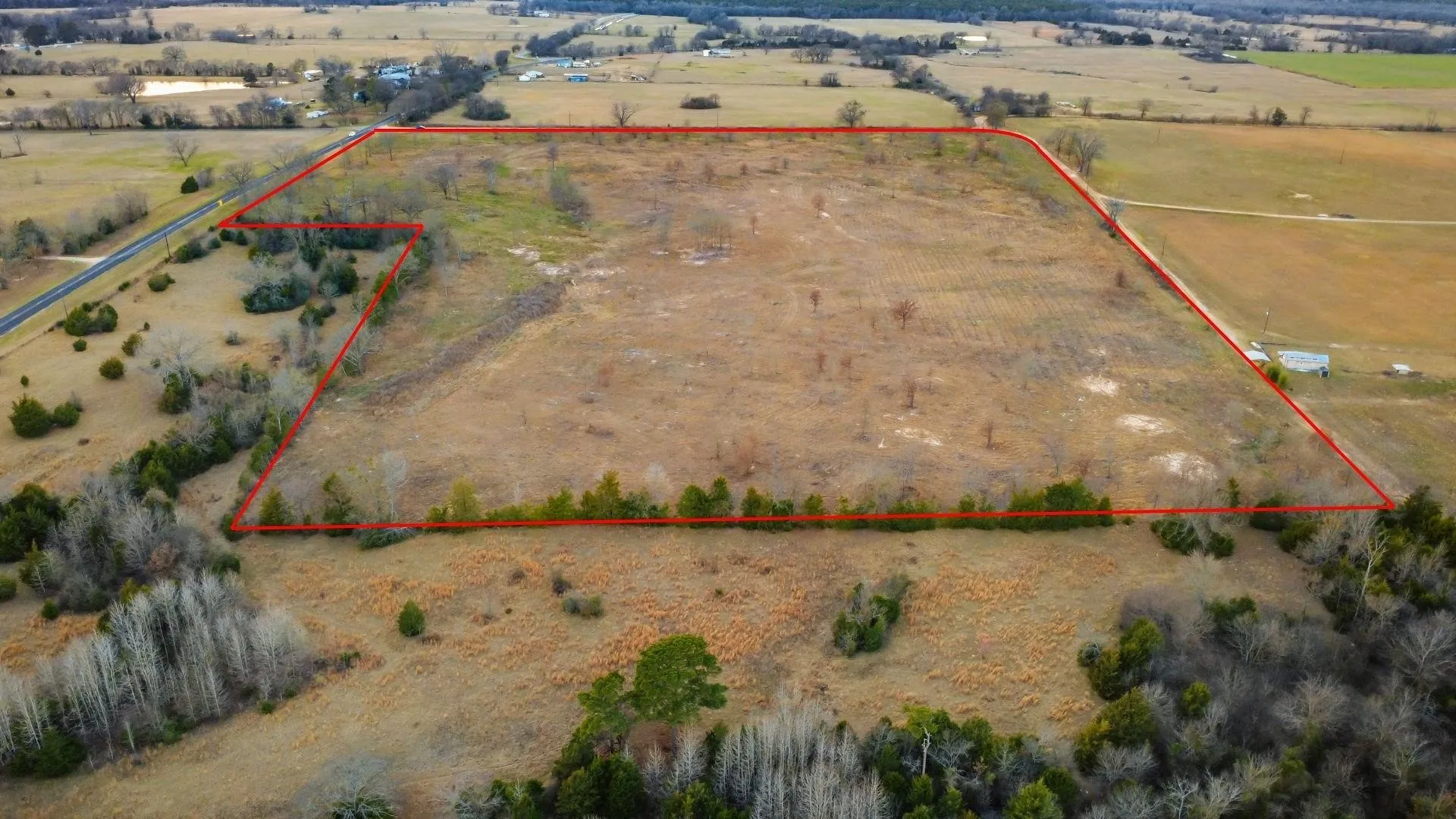 Expansive rural land parcel featuring a mix of open fields and natural tree lines