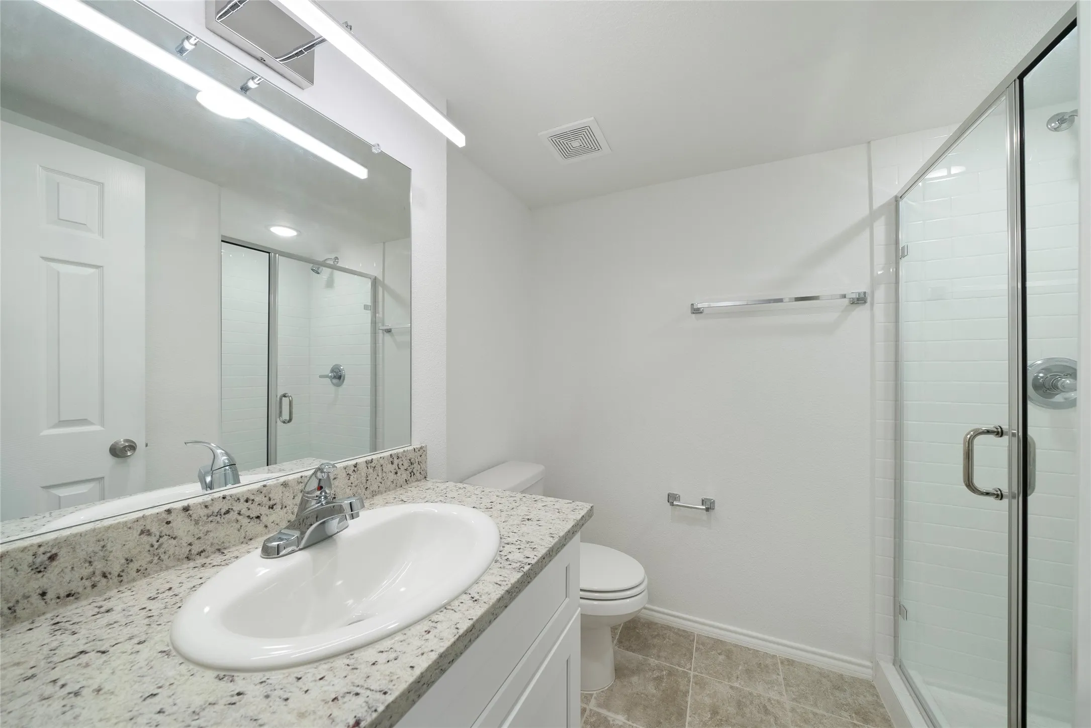 Contemporary bathroom featuring a single vanity with stone countertop, undermount sink, and chrome faucet