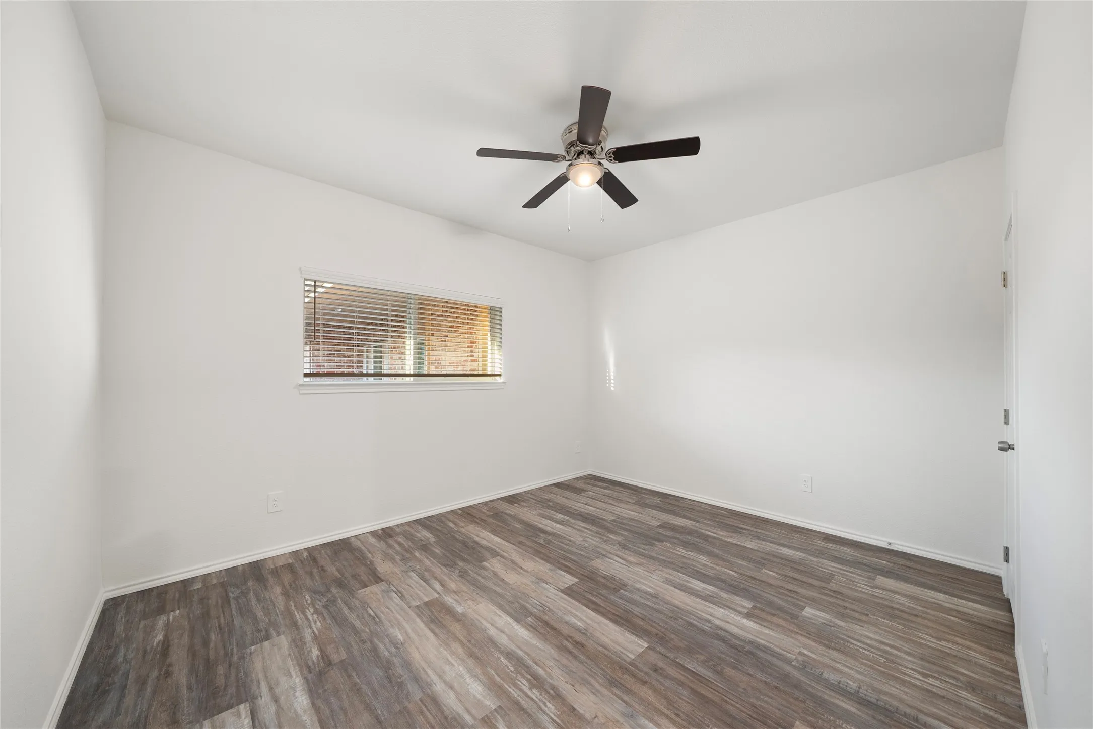 Room featuring a ceiling fan with light kit, wood-finish flooring, and a window with blinds