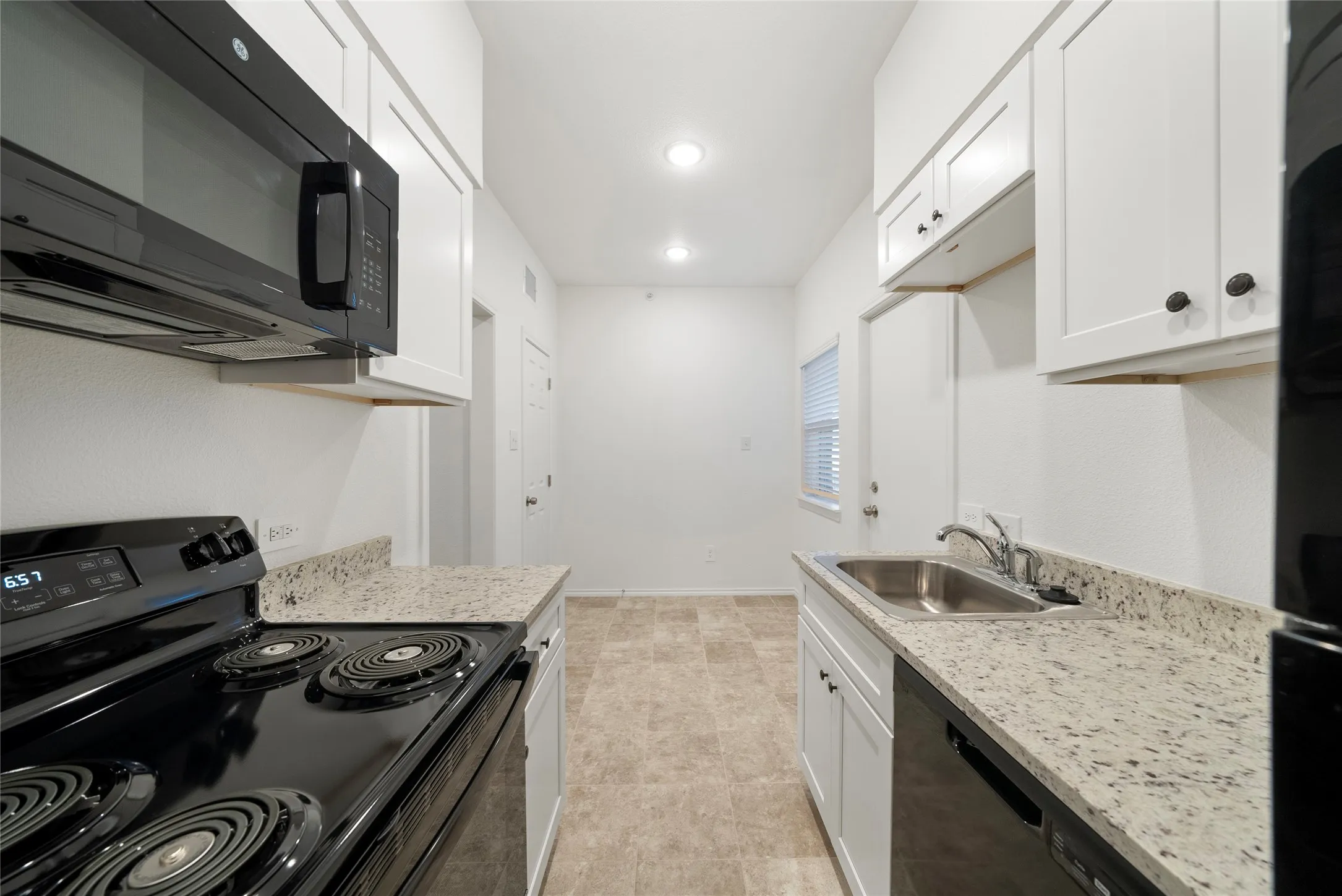Kitchen featuring white shaker cabinetry, speckled countertops, black appliances, and recessed lighting