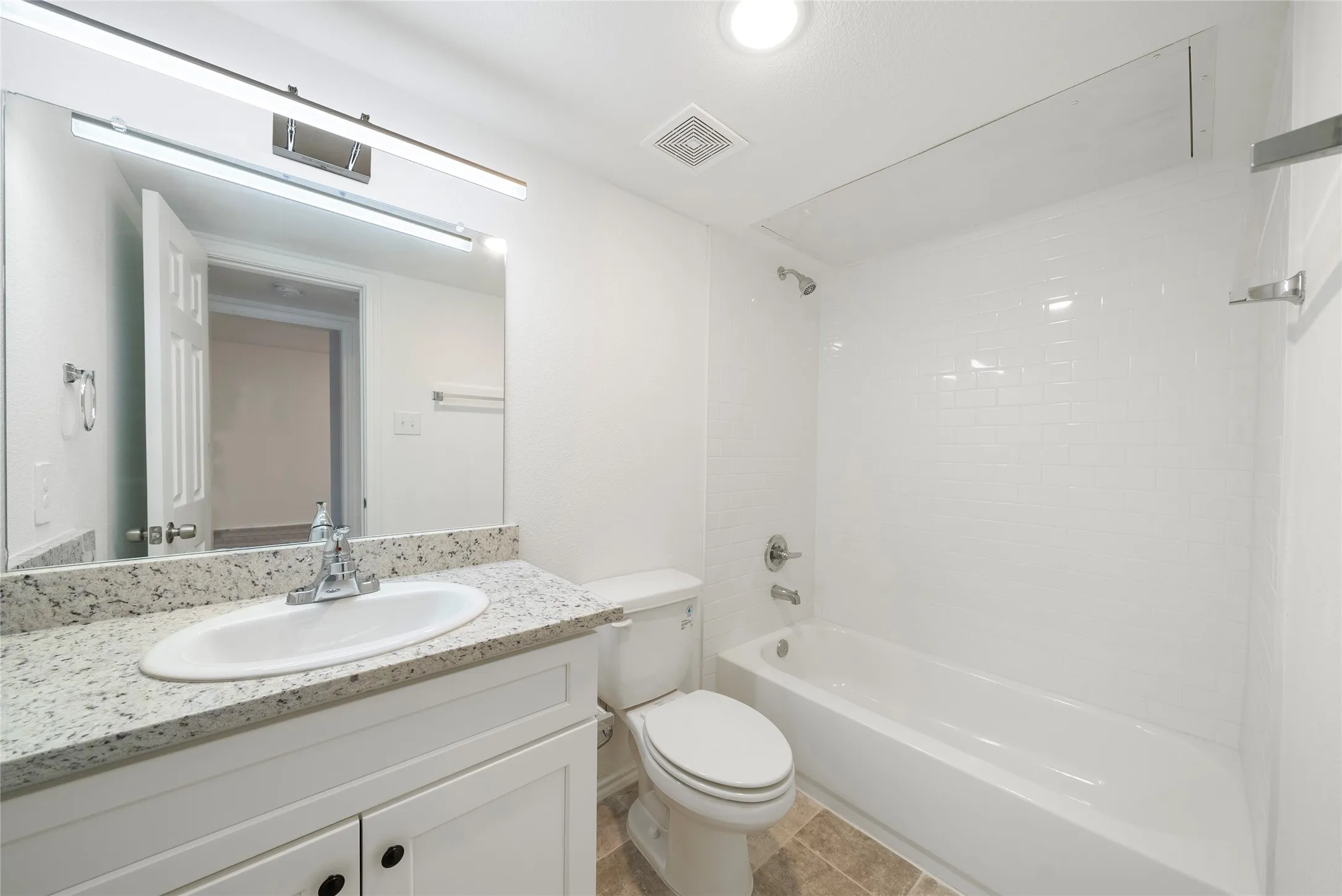 Bathroom featuring a white vanity with a granite-style countertop, undermount sink, and chrome faucet