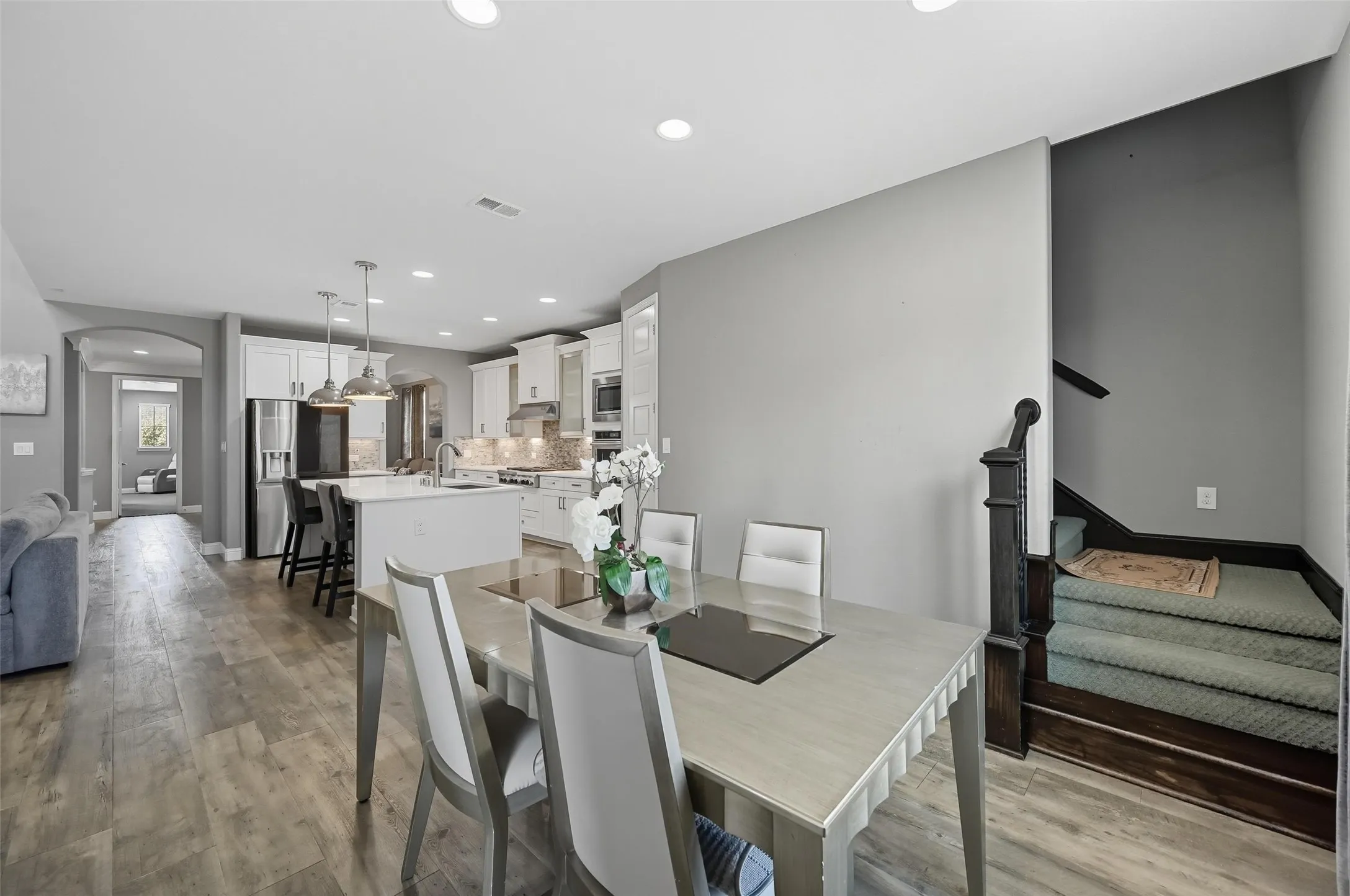Open-concept living space featuring wood-finish flooring, recessed lighting, and a contemporary kitchen with stainless steel appliances