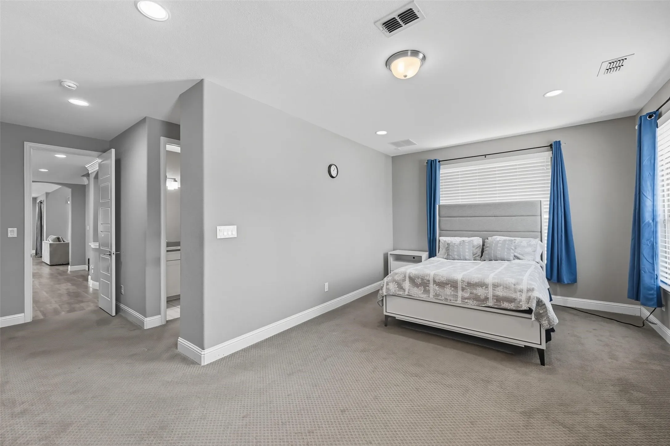 Carpeted room featuring multiple recessed lights, a window with blinds, and white baseboards