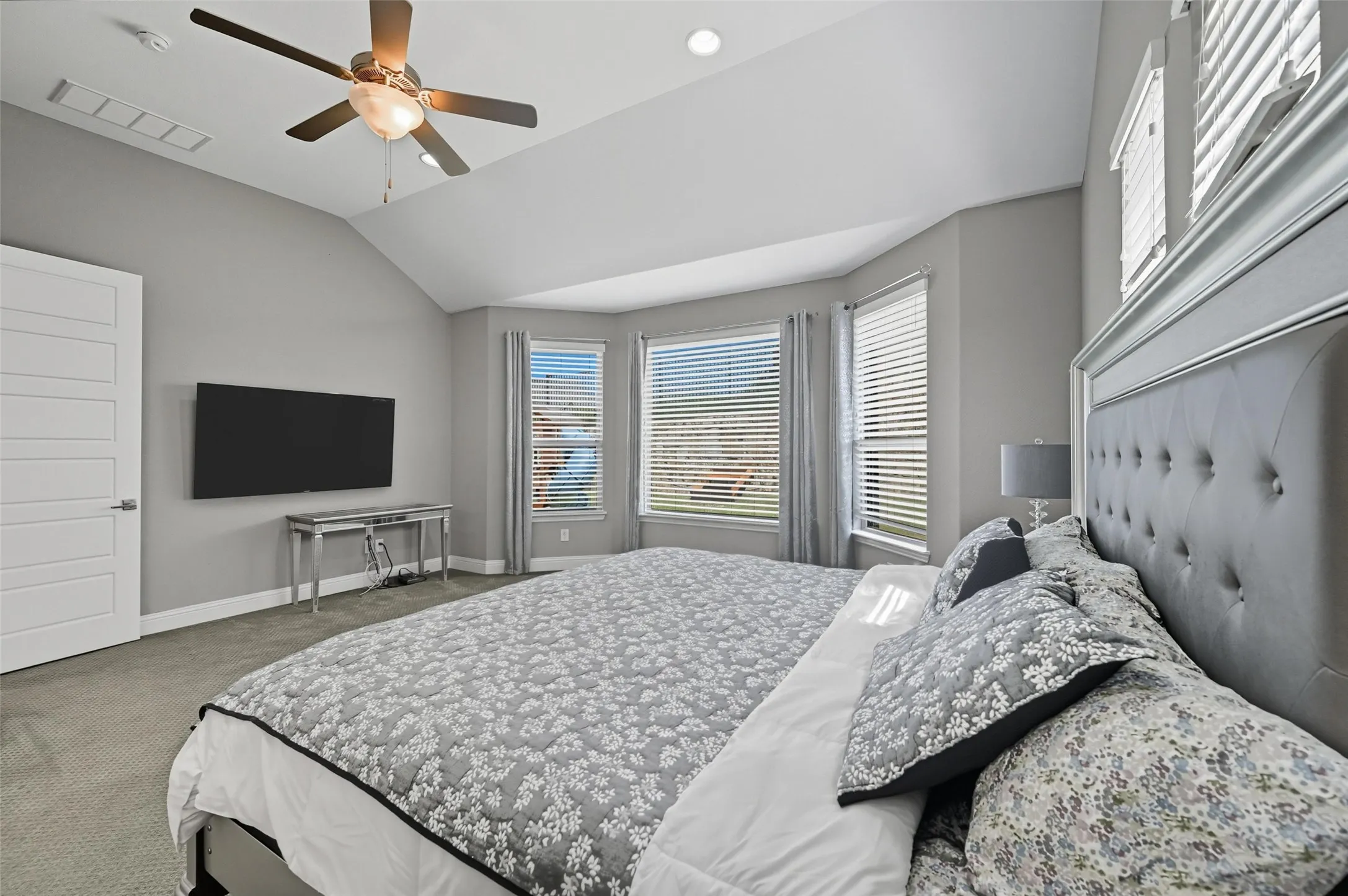 Carpeted room with a vaulted ceiling and a ceiling fan